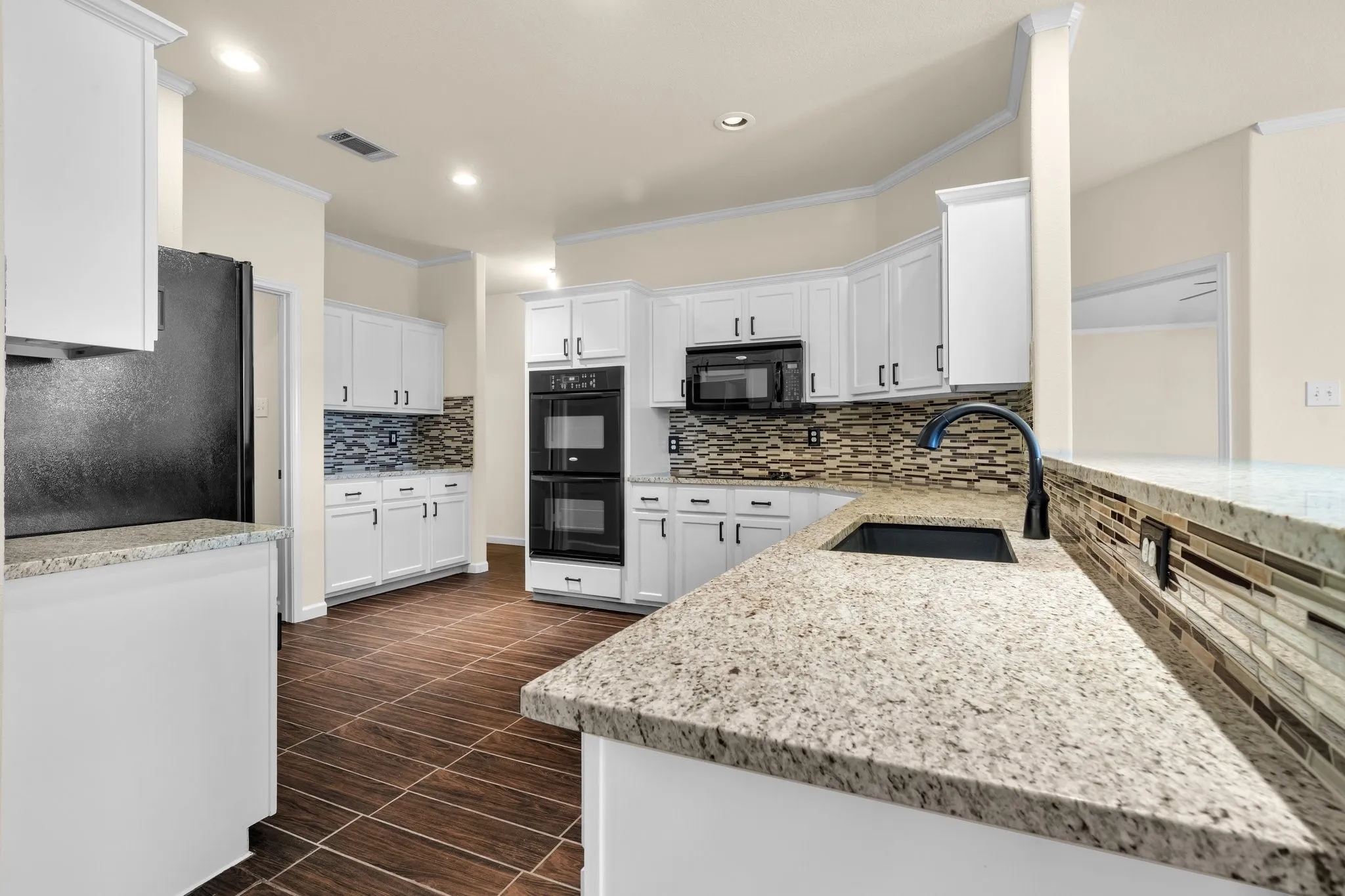 Kitchen featuring white cabinetry, built-in double ovens, dark wood-finish tile flooring, granite countertops, and a tile backsplash