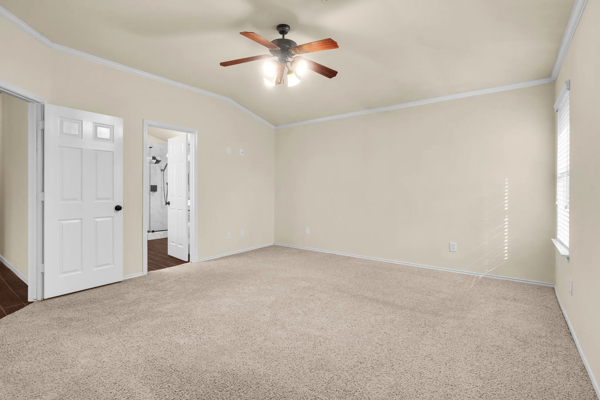 Tray ceiling with crown molding, ceiling fan, carpet flooring, window with blinds, and white paneled doors