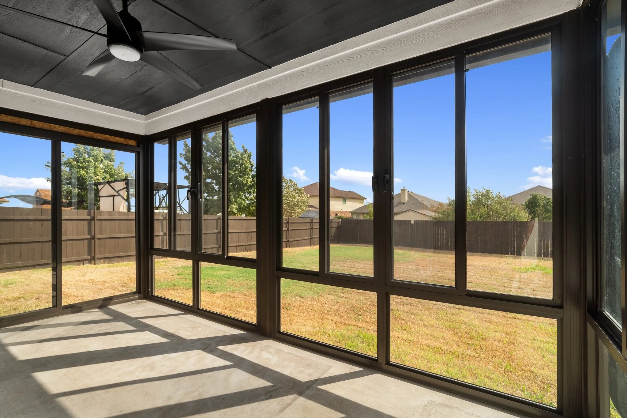 Enclosed patio featuring a ceiling fan, concrete flooring, and multiple window panels