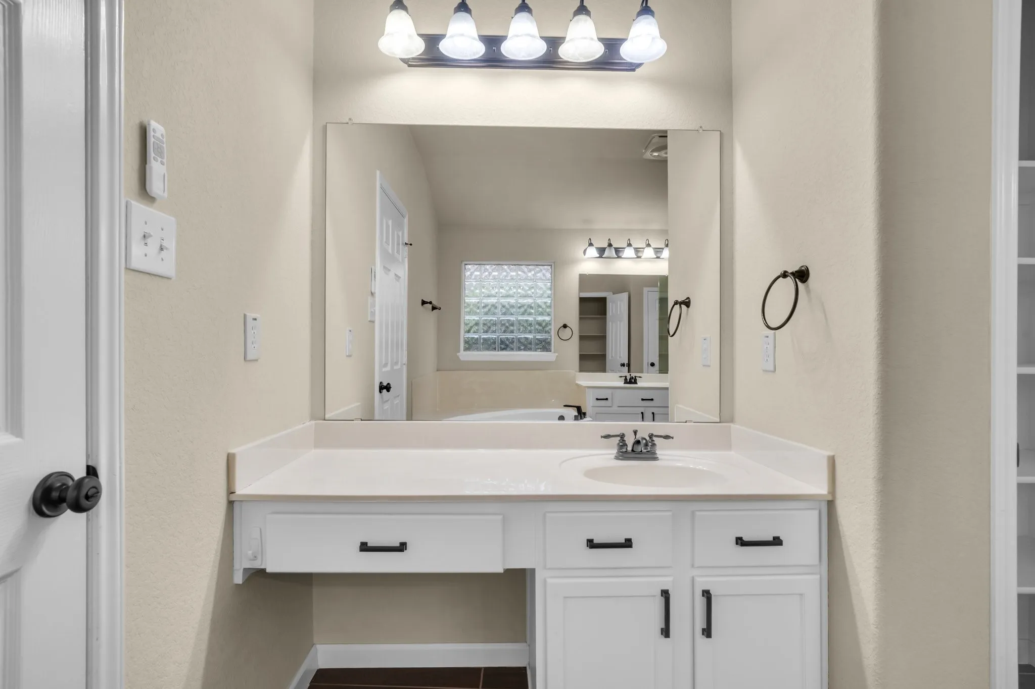 Vanity with integrated sink, white cabinetry, and matte black hardware