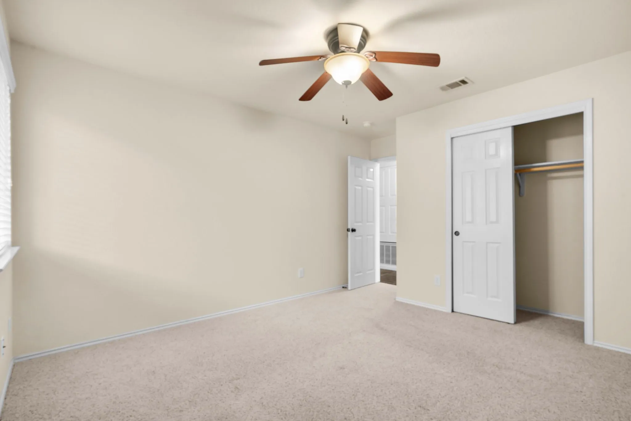 Recessed window, ceiling fan with integrated lighting, neutral wall tones, sliding closet doors, and light-toned carpeting