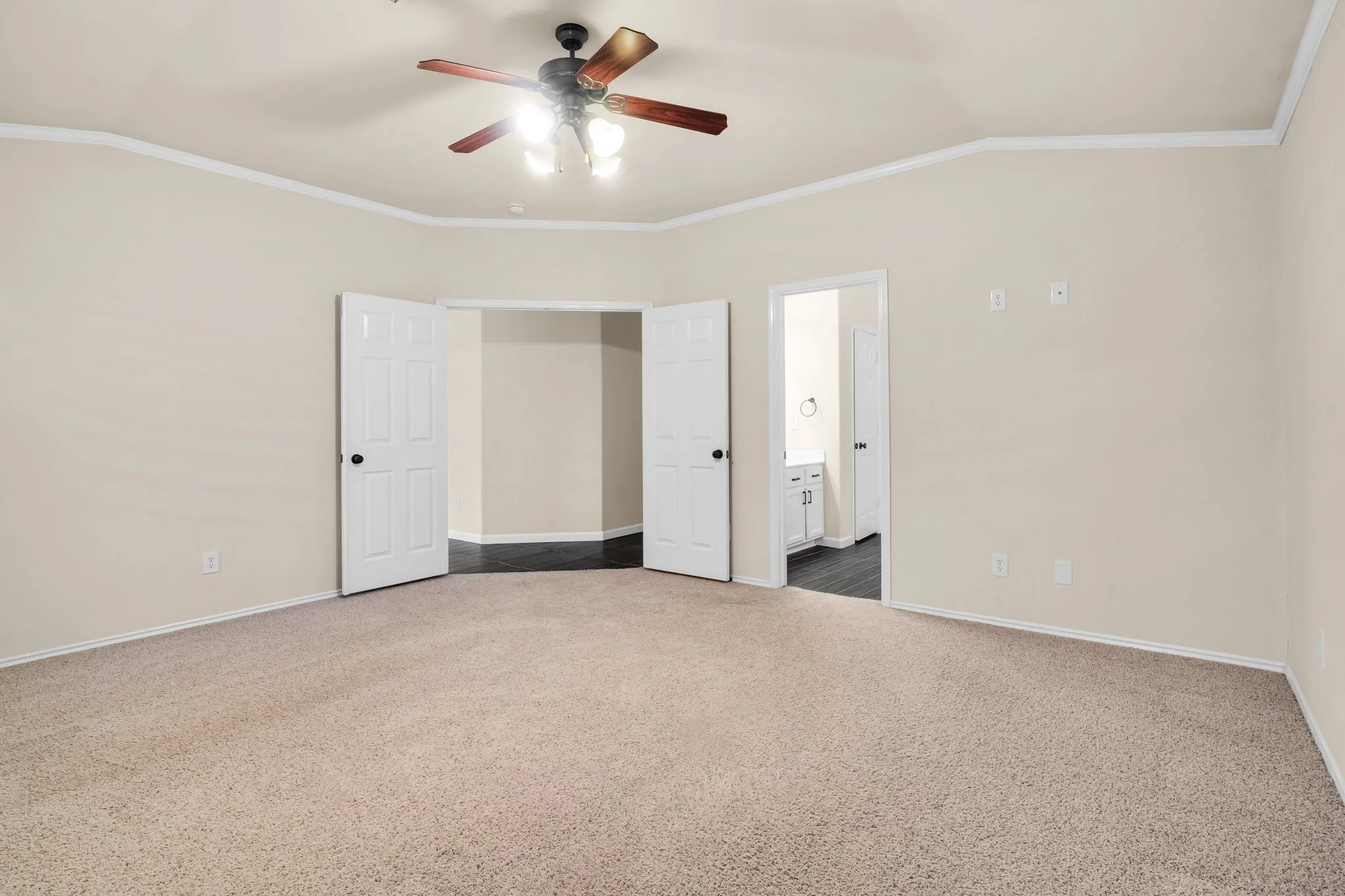 Carpeted room with a ceiling fan, crown molding, and two panel doors