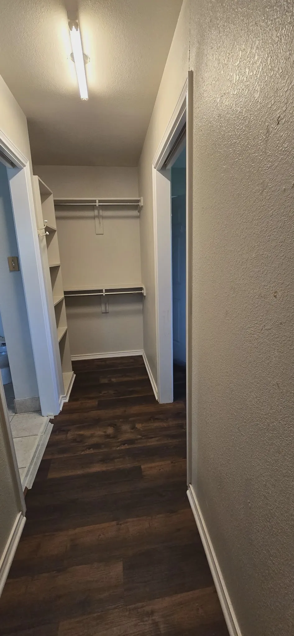 Walk-in closet with built-in shelving, dual hanging rods, and wood-finish flooring