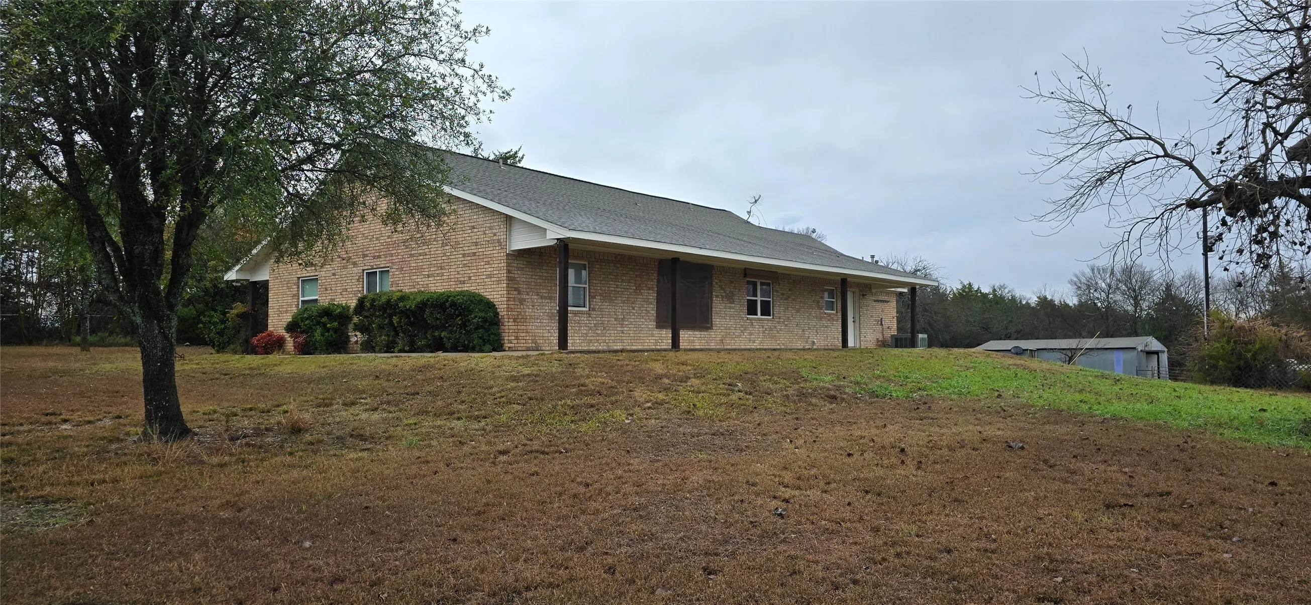 Brick exterior with a covered porch and a shingle roof
