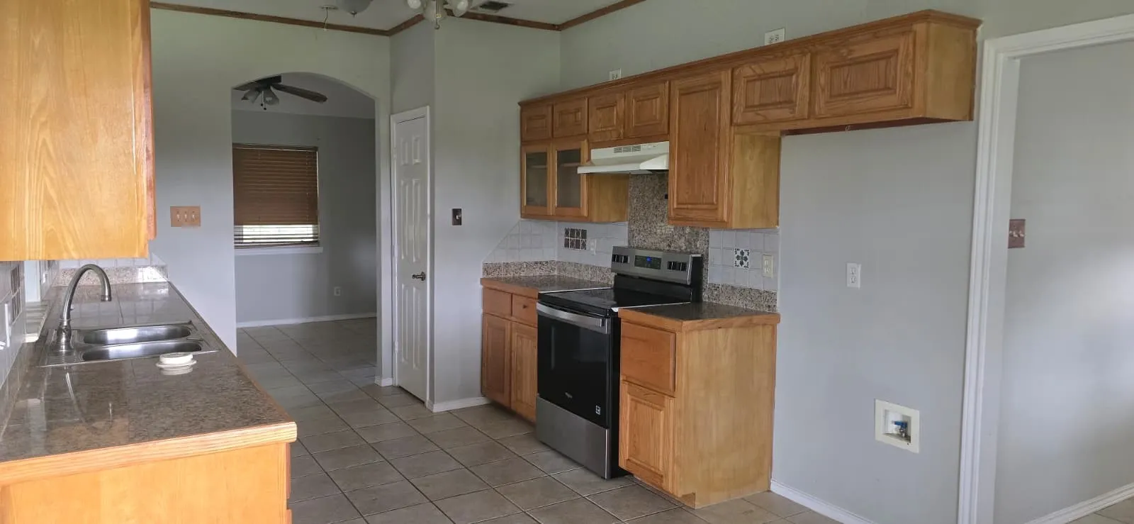 Kitchen featuring tile flooring, wood-finish cabinetry, granite-style countertops, and a stainless steel electric range