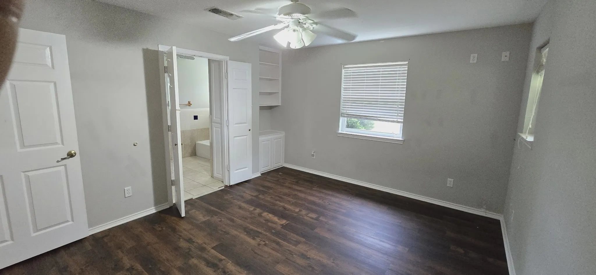 Wood-finish flooring, ceiling fan, built-in shelving, built-in storage cabinet, and window with blinds