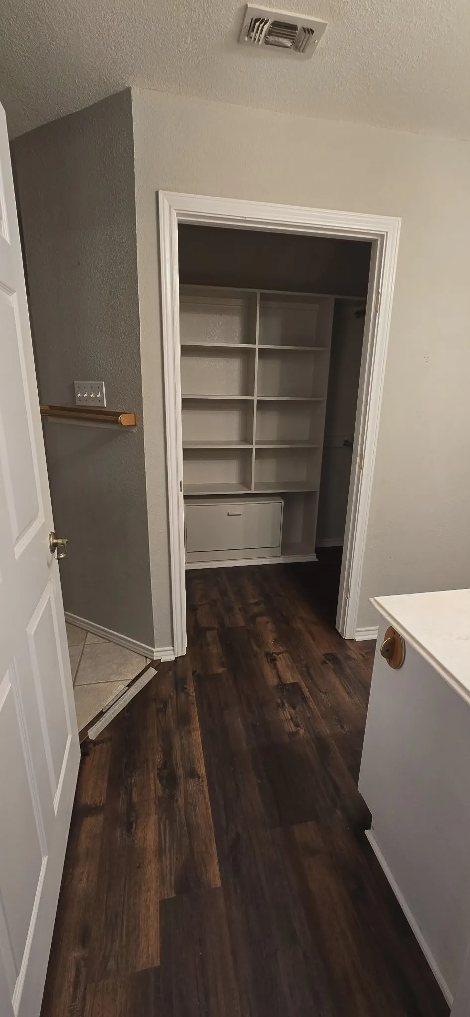 Dark wood-finish flooring throughout, white built-in shelving, white baseboards, and light-toned wall paint