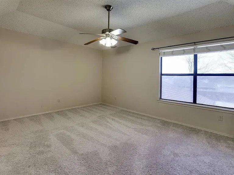 Recessed ceiling, ceiling fan with integrated lighting, large window with roller shade, and plush carpet flooring
