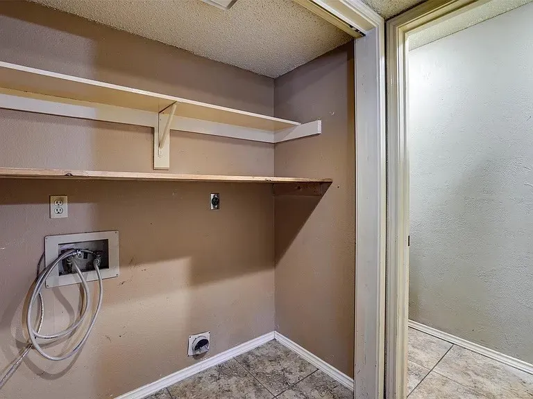 Laundry area featuring neutral wall paint, built-in shelving, and tile flooring