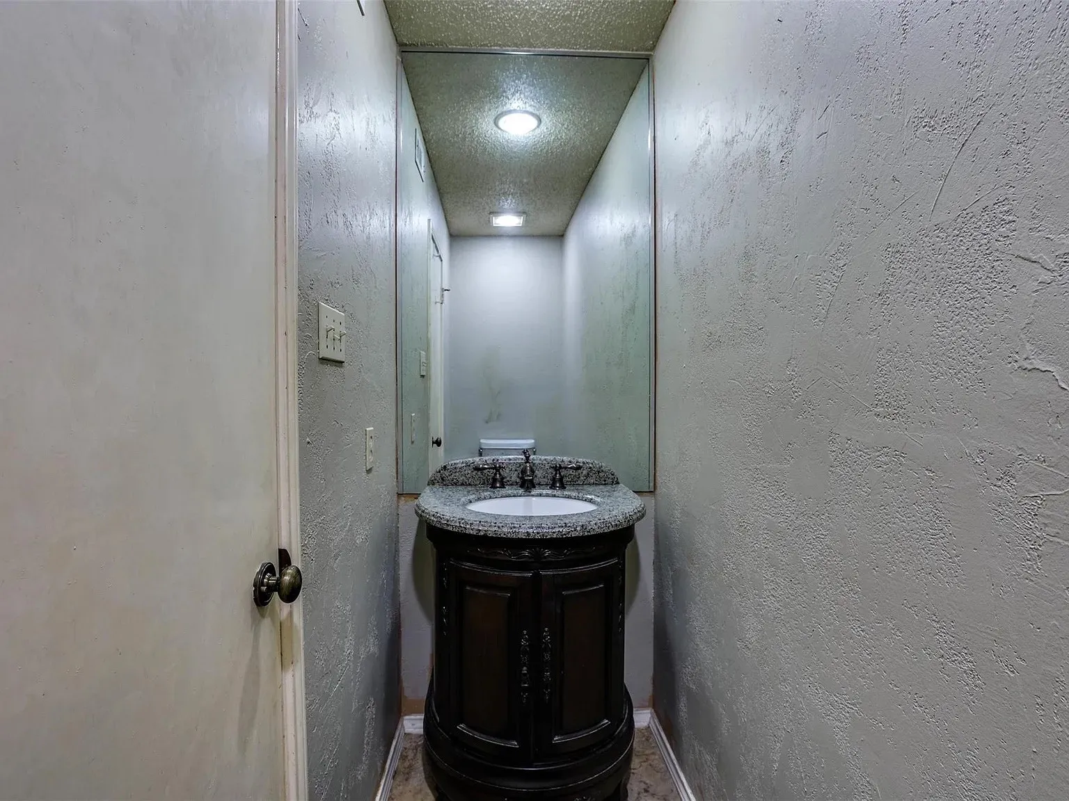 Recessed lighting, a dark wood-finish vanity, a stone-finish countertop, an undermount sink, and a large wall mirror