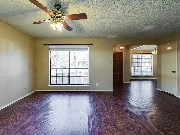 Wood-finish flooring throughout, ceiling fan with integrated lighting, and multiple windows with blinds