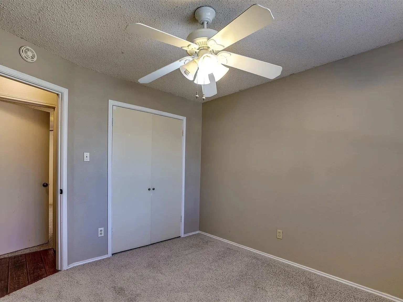 Neutral-toned wall finish, carpeted flooring, permanent ceiling fan with light, and built-in closet with double doors