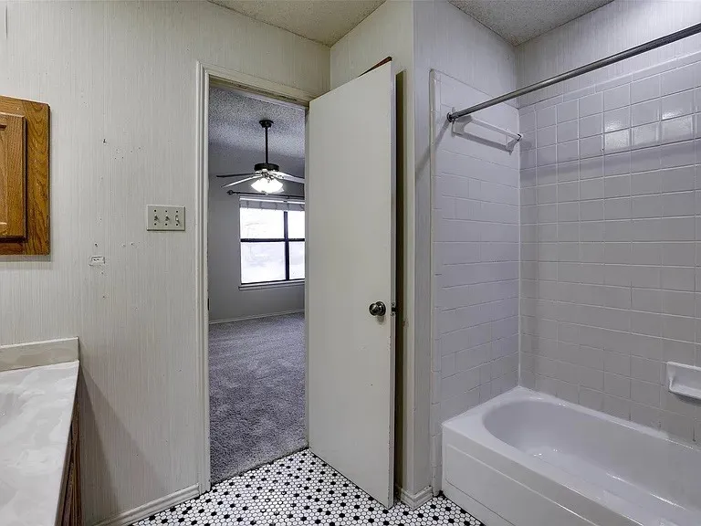 Bathroom featuring a white bathtub, white subway tile surround, and a black and white hex tile floor