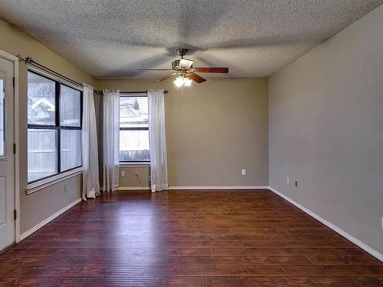 Wood-finish flooring, multiple windows, ceiling fan, and neutral wall tones
