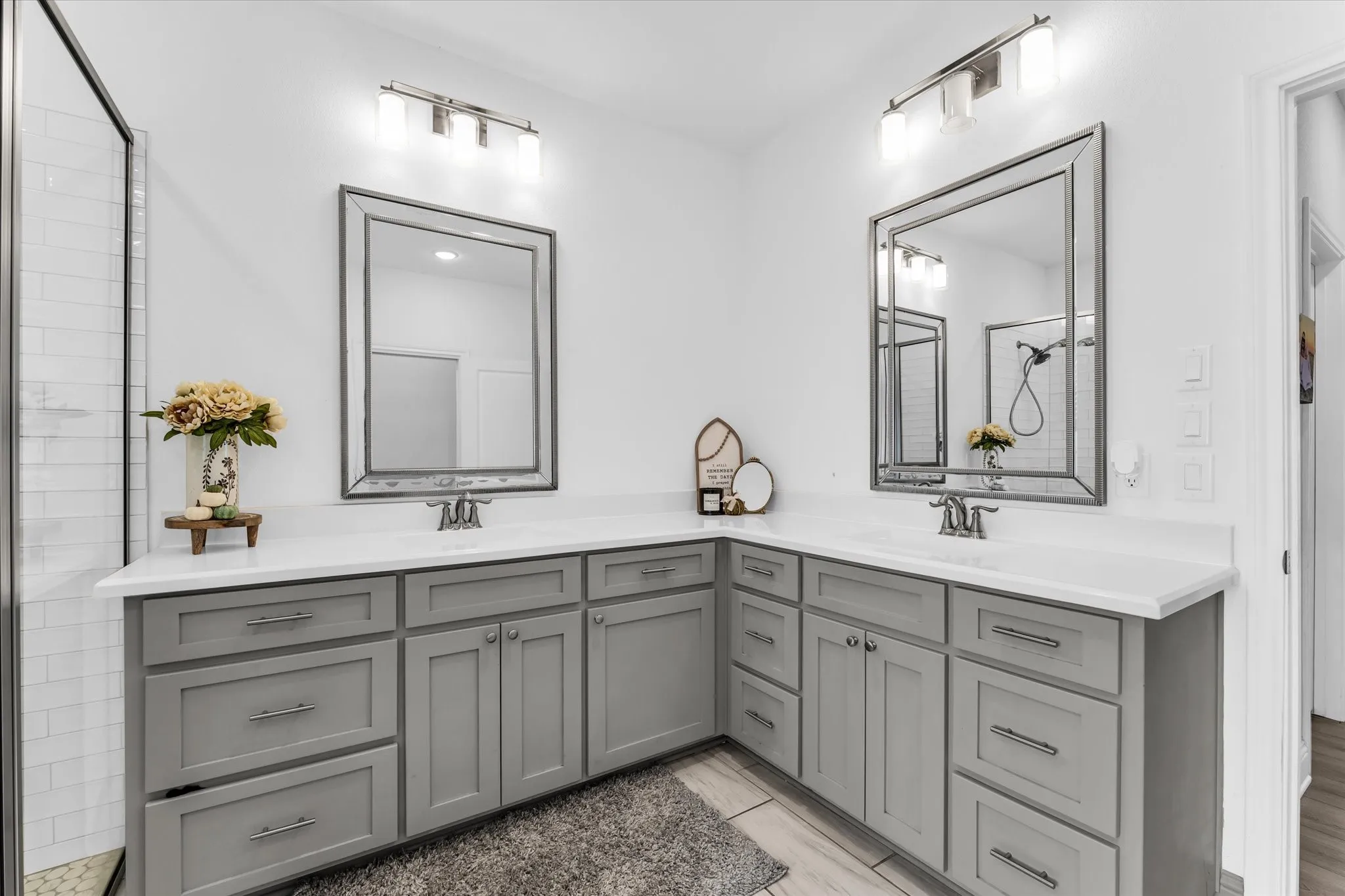 Dual vanity with light gray cabinetry, white countertops, and framed mirrors