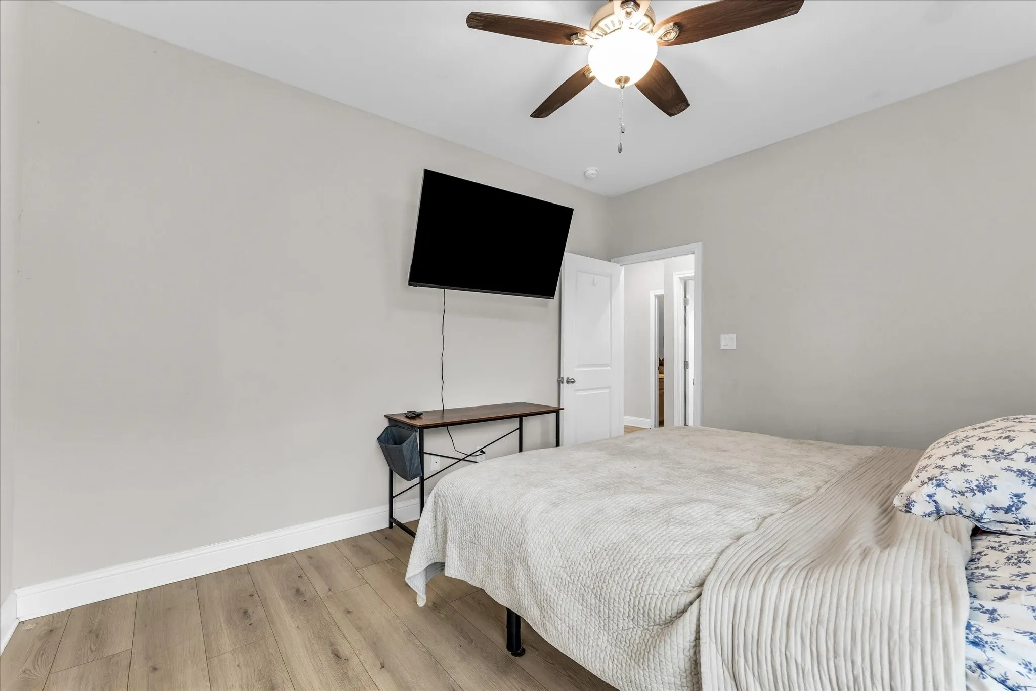 Wood-finish flooring with light gray walls, white trim, and a ceiling fan with integrated lighting