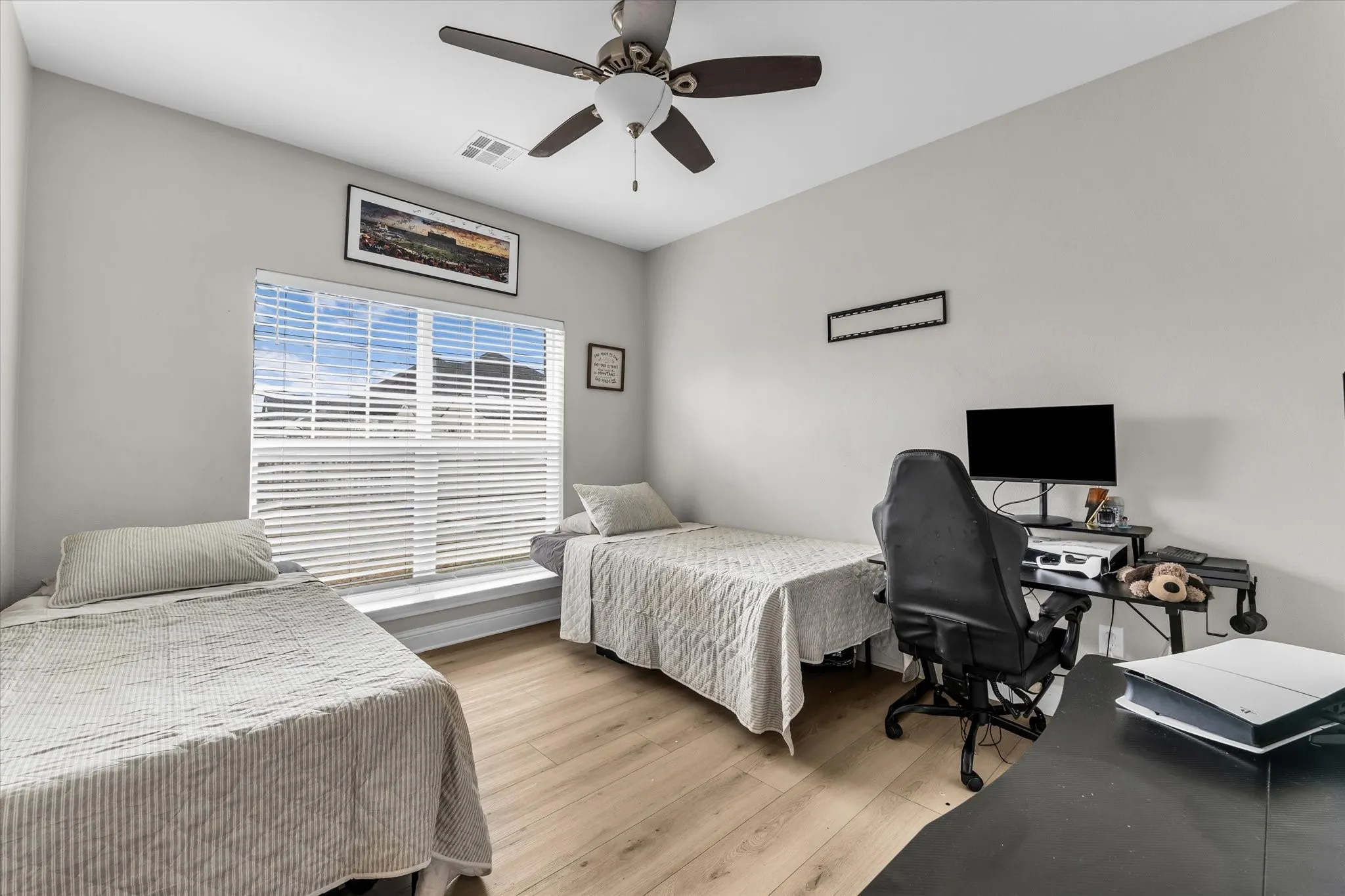 Room featuring wood-finish flooring, a ceiling fan, and a window with blinds