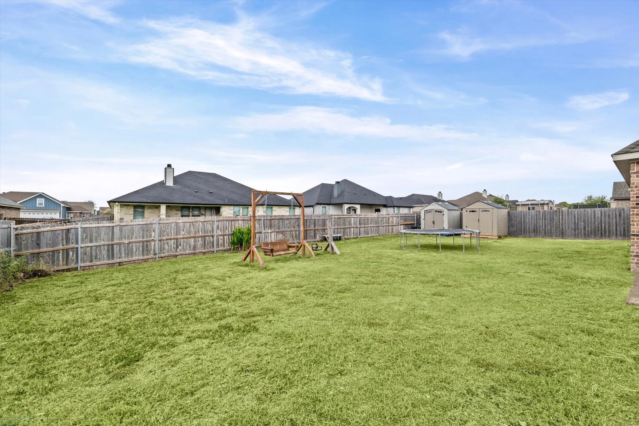 Expansive grass lawn with wood privacy fencing and two storage sheds
