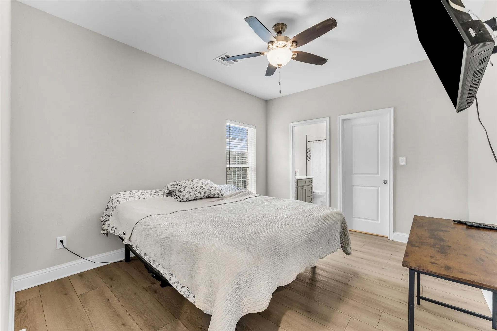 Recessed window with blinds, wood-finish flooring, ceiling fan with light fixture, and white interior doors