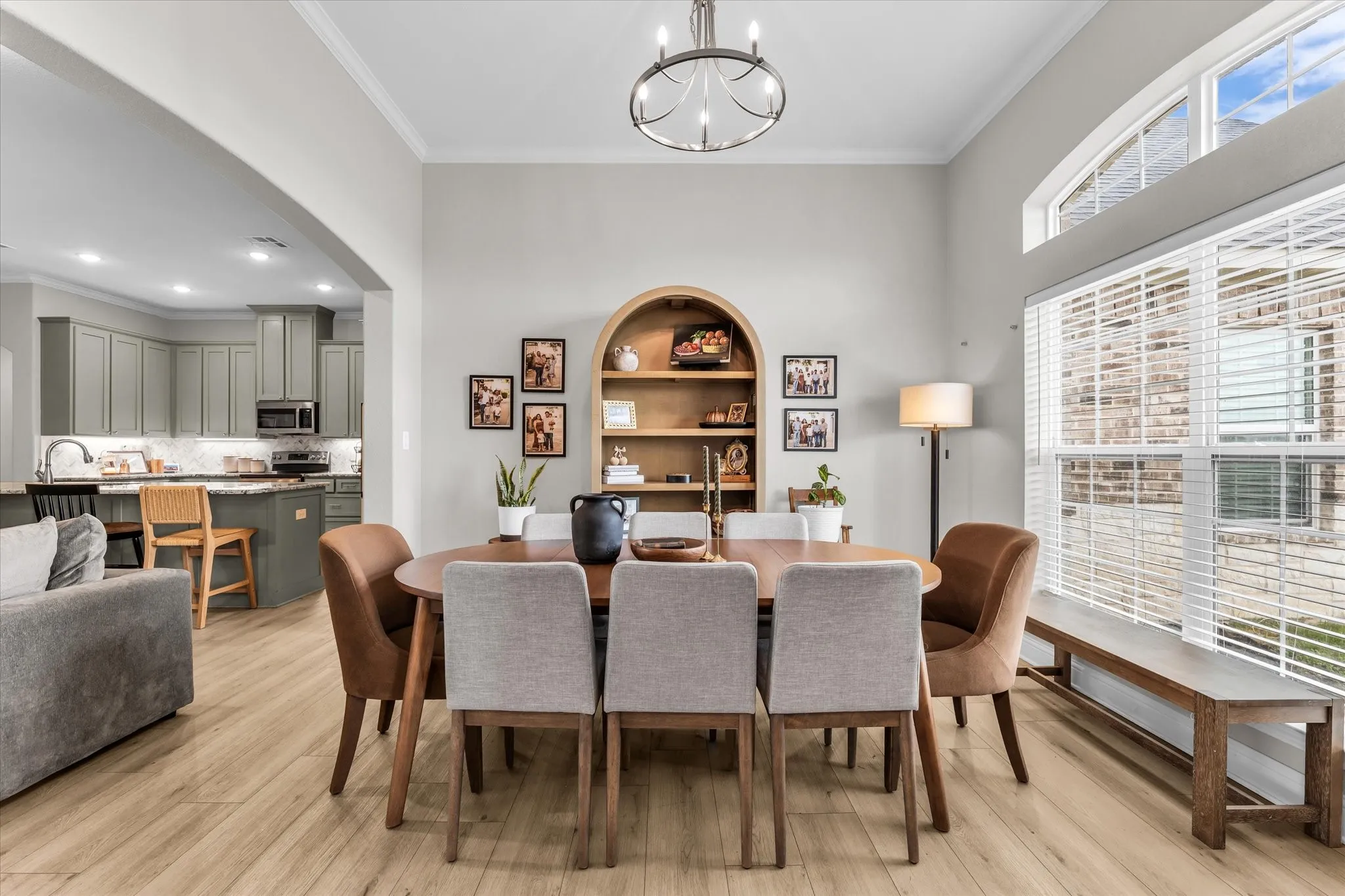 Open-concept living space featuring wood-finish flooring, a contemporary chandelier, and a kitchen with gray cabinetry and stainless steel appliances