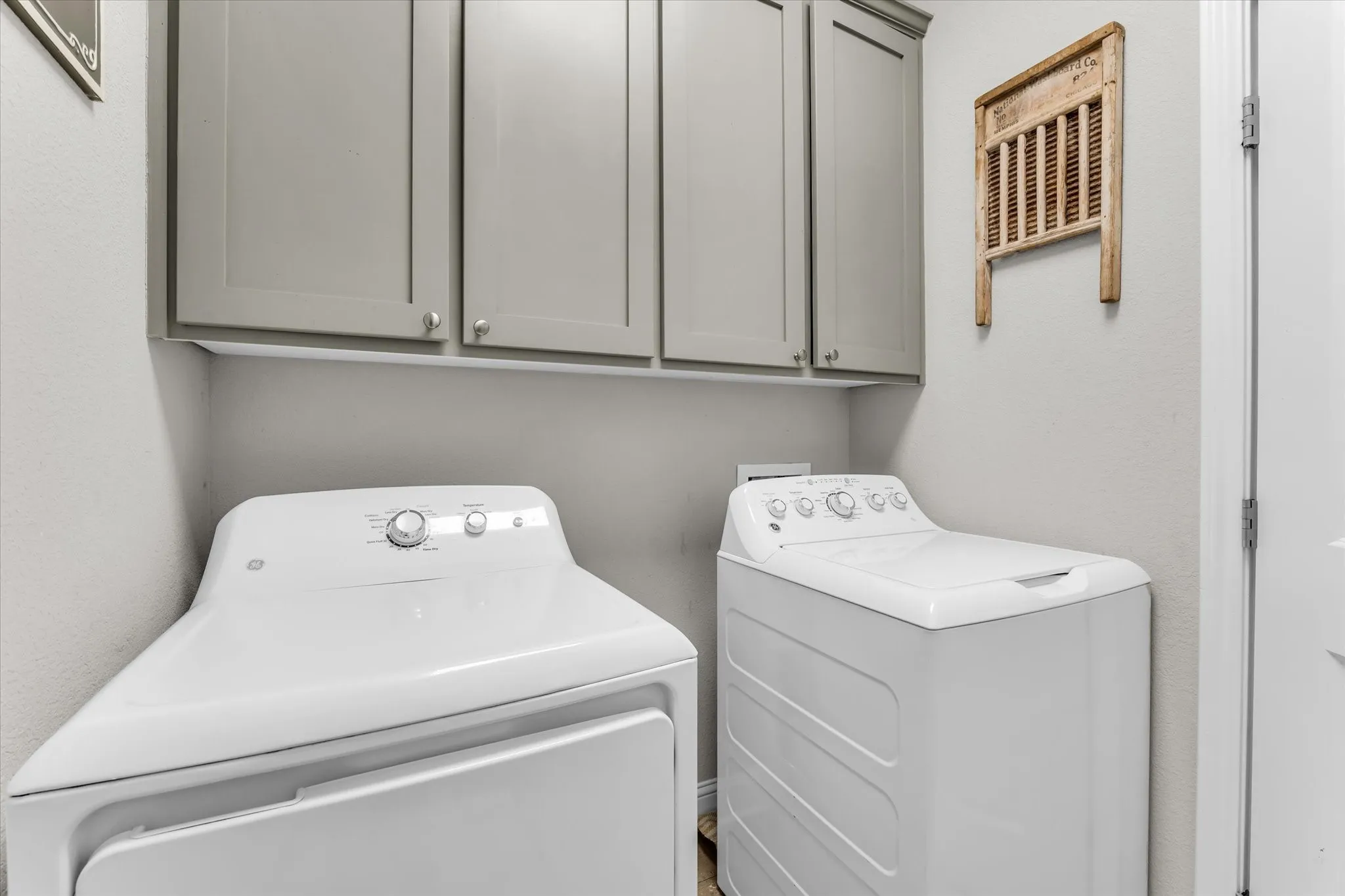 Utility area with upper cabinetry and a light gray finish