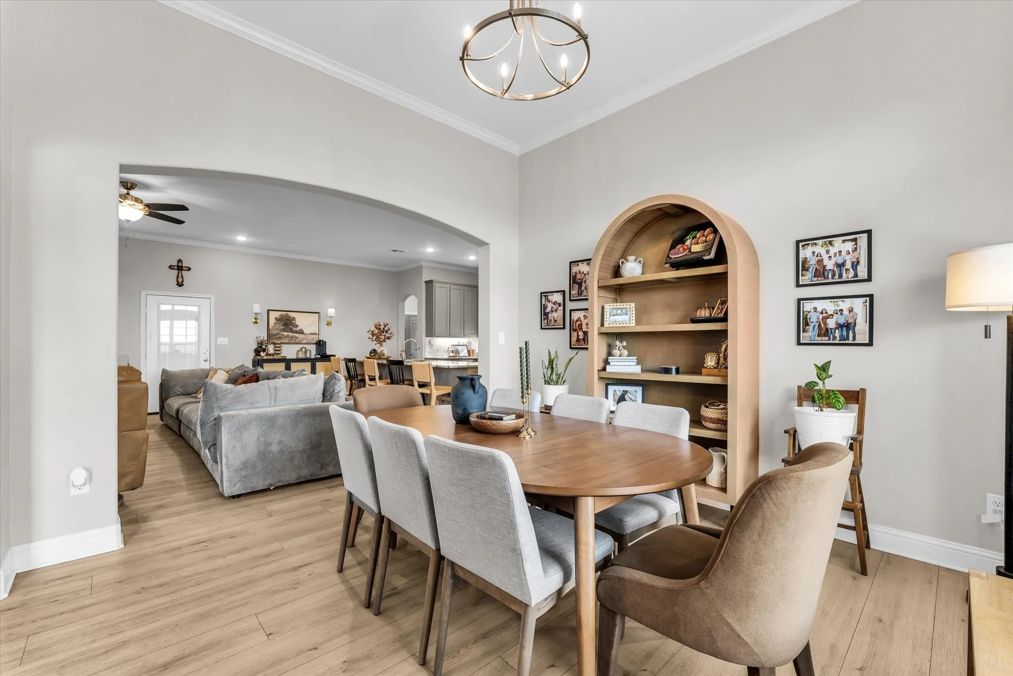 Vaulted ceiling with crown molding, wood-finish flooring, and an arched entryway