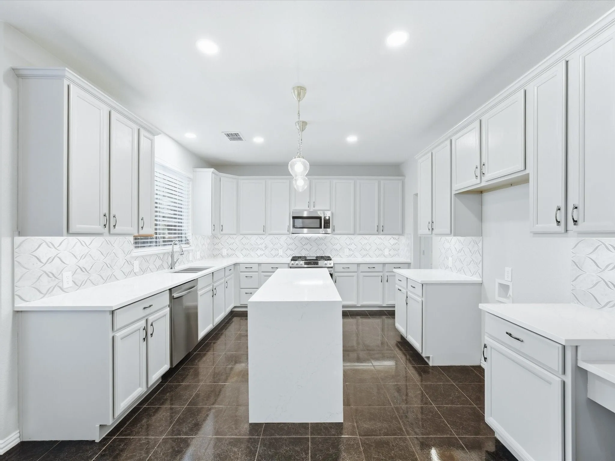 Kitchen featuring a central island, white shaker-style cabinetry, white countertops, and a patterned tile backsplash
