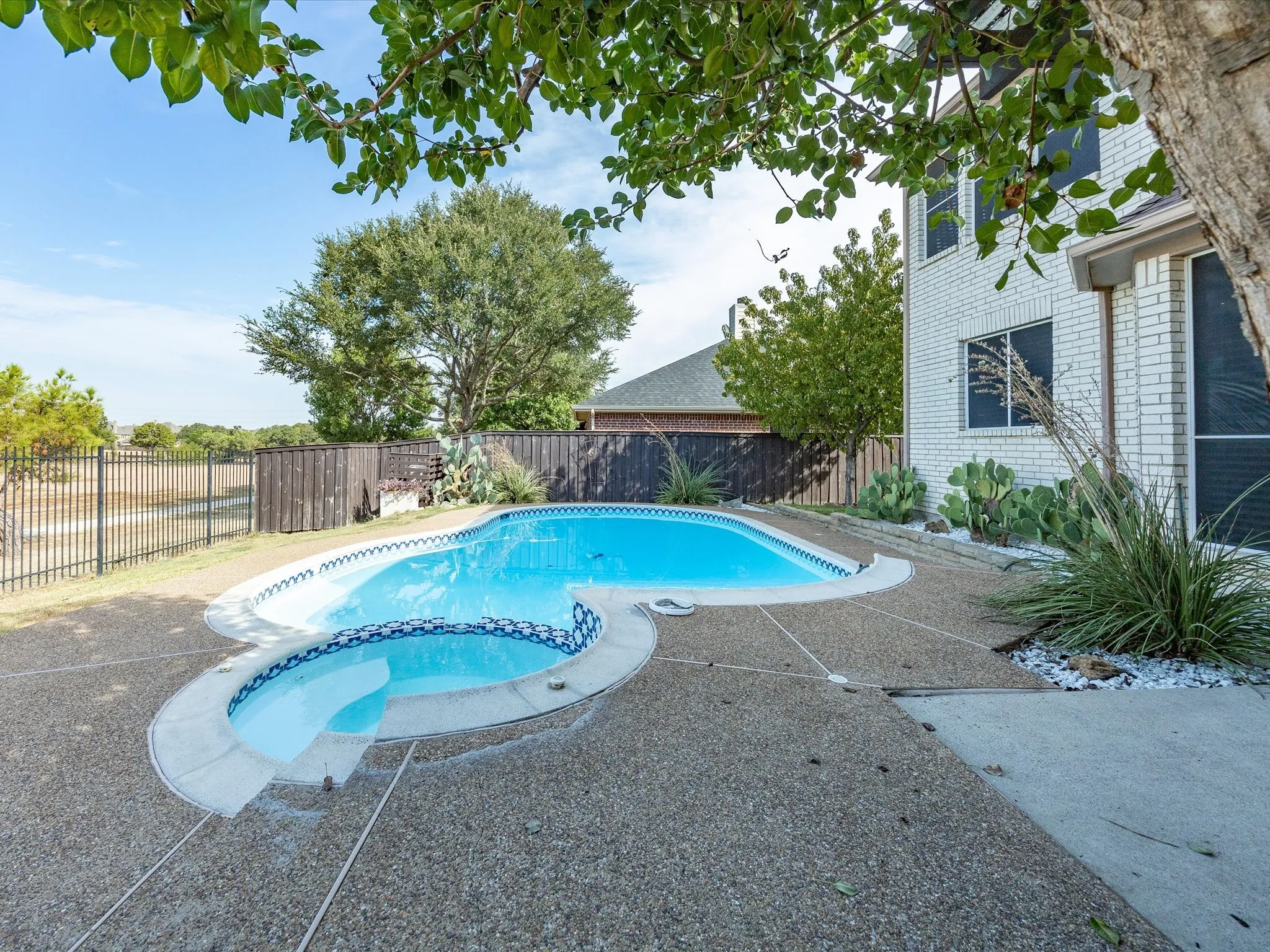 In-ground swimming pool with an integrated spa, complemented by an exposed aggregate concrete deck