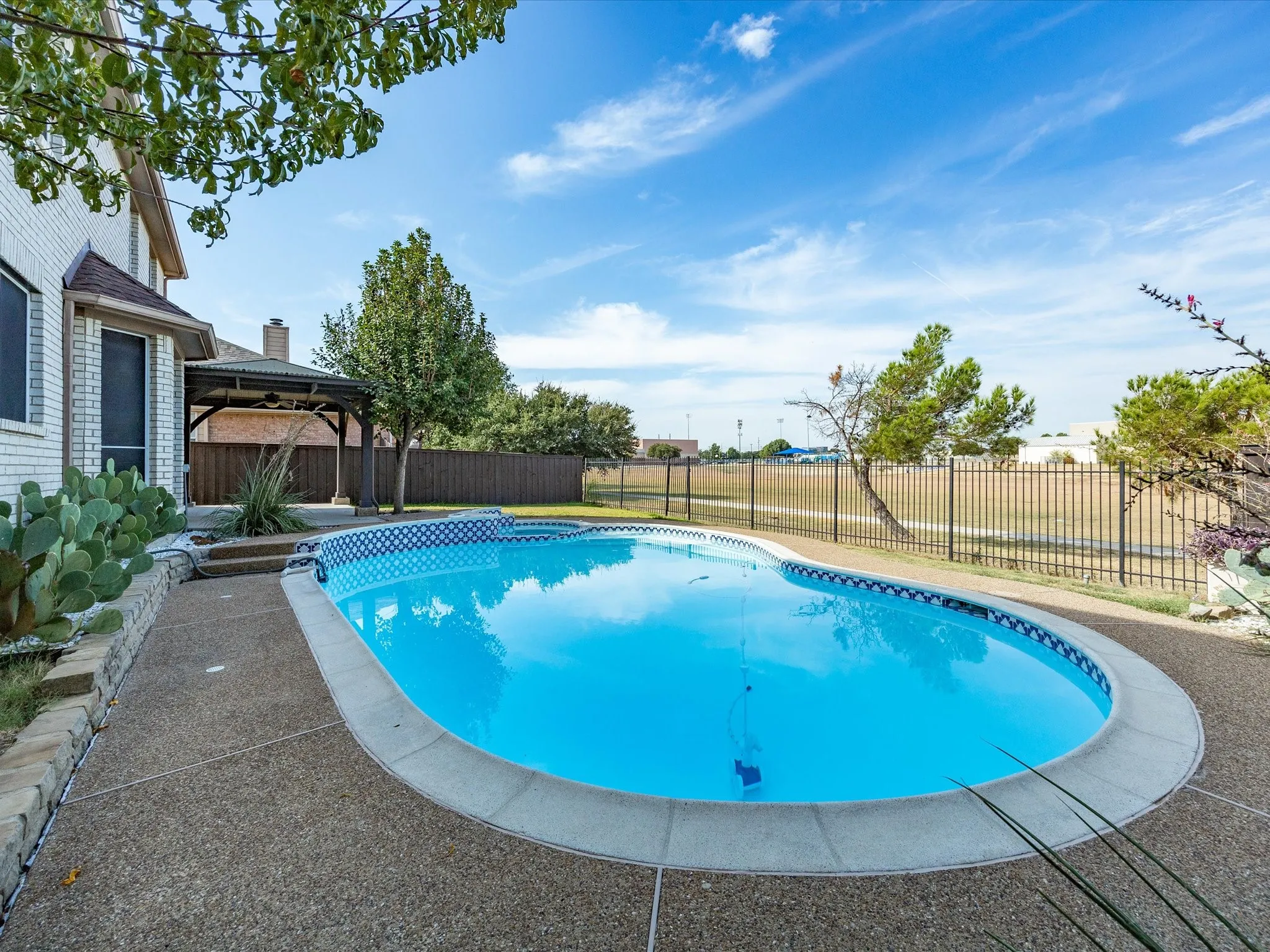 Backyard features a freeform swimming pool, concrete patio, and an adjacent gazebo