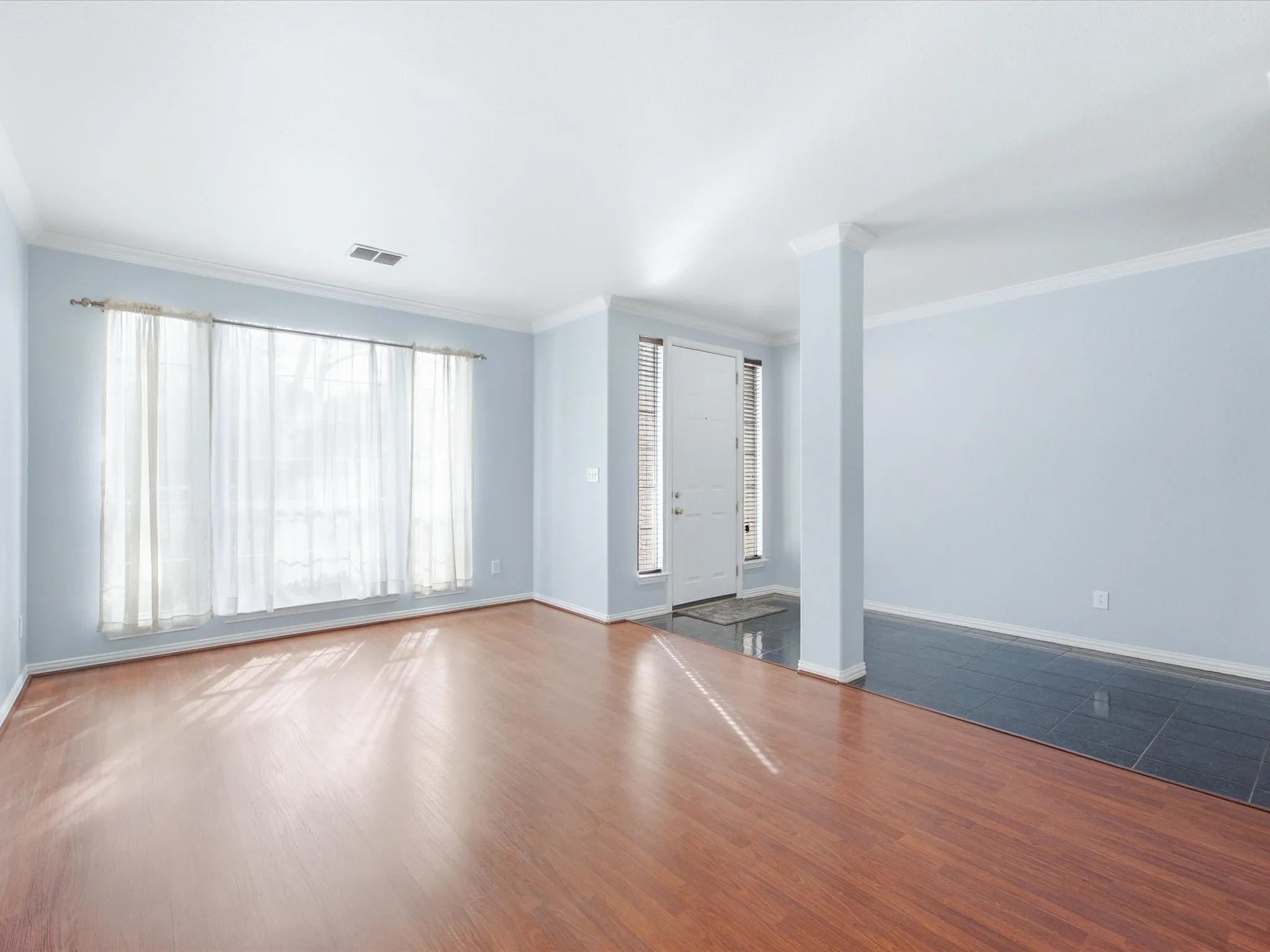 Crown molding, wood-finish flooring, column accent, front entry door, tiled entry
