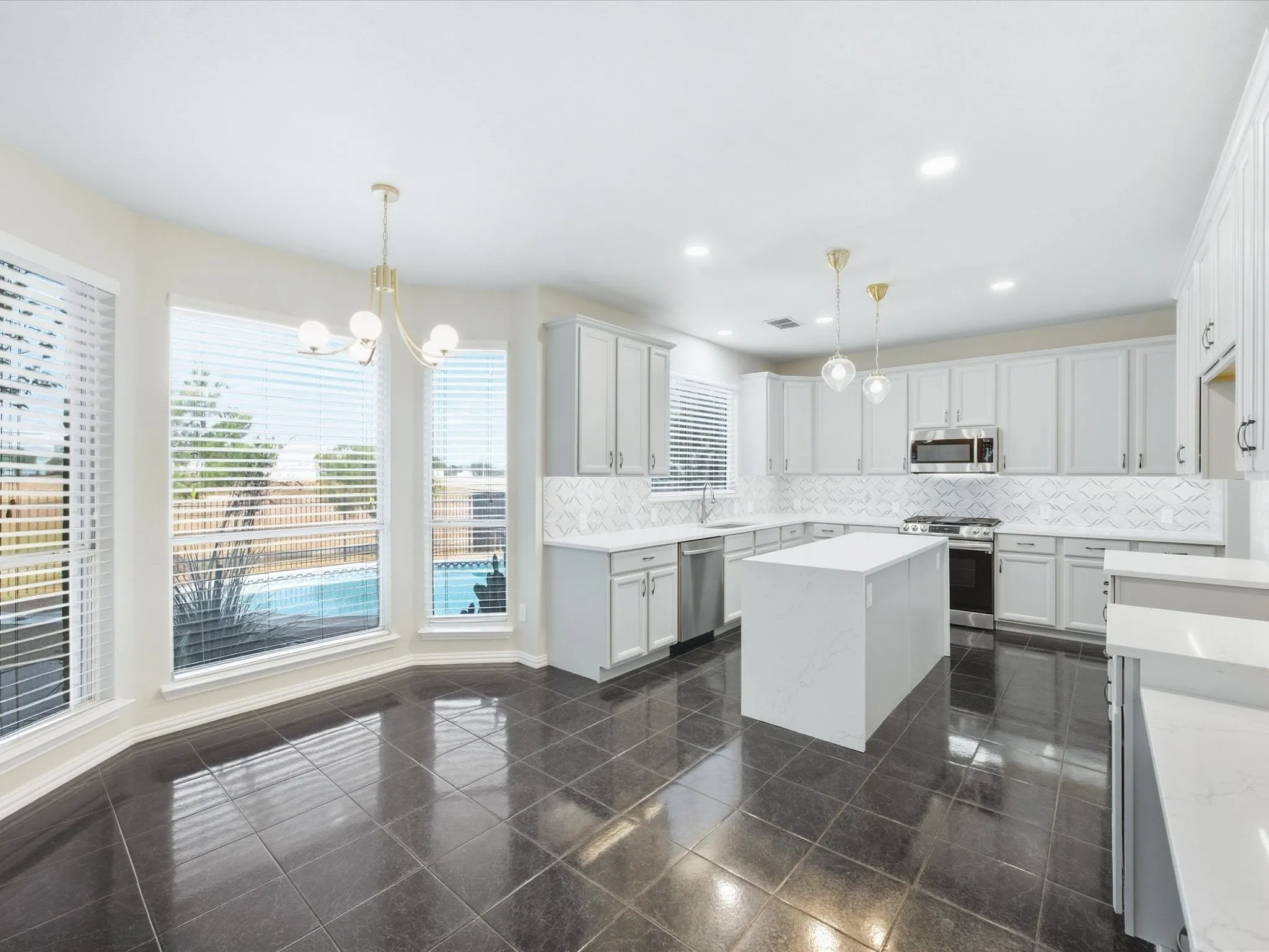 Contemporary kitchen featuring white cabinetry, stainless steel appliances, and a large center island with white quartz countertops
