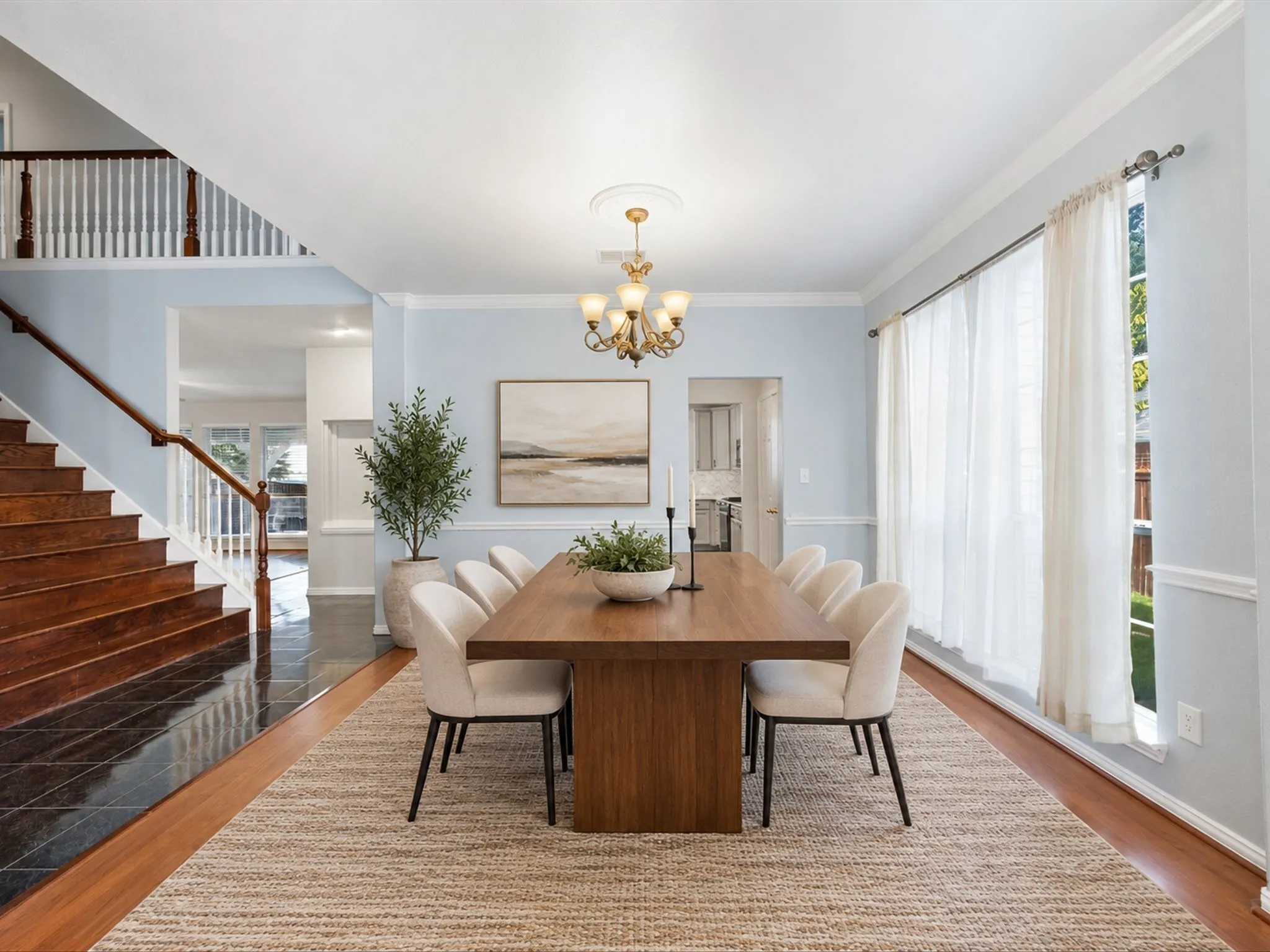 Wood-finish flooring, staircase with wood handrail, crown molding, double windows, and chandelier