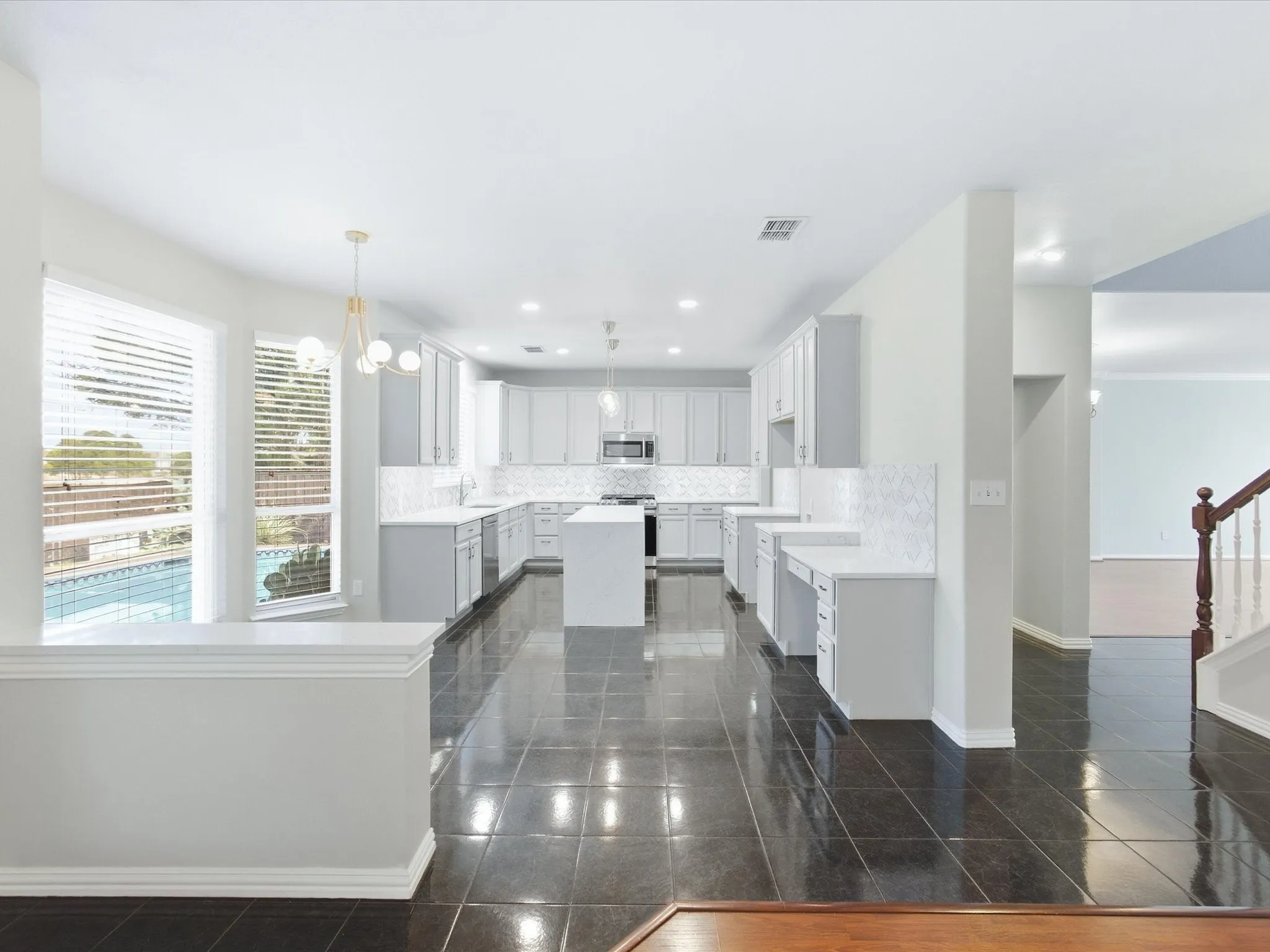 Spacious kitchen with a central island, recessed lighting, and a window overlooking a swimming pool