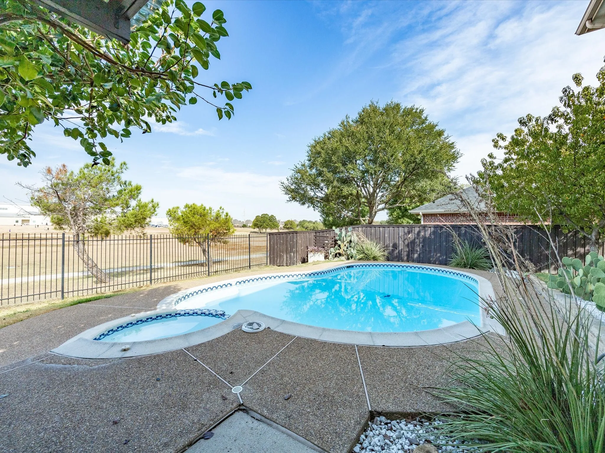 Outdoor pool with an integrated spa, surrounded by an exposed aggregate concrete deck