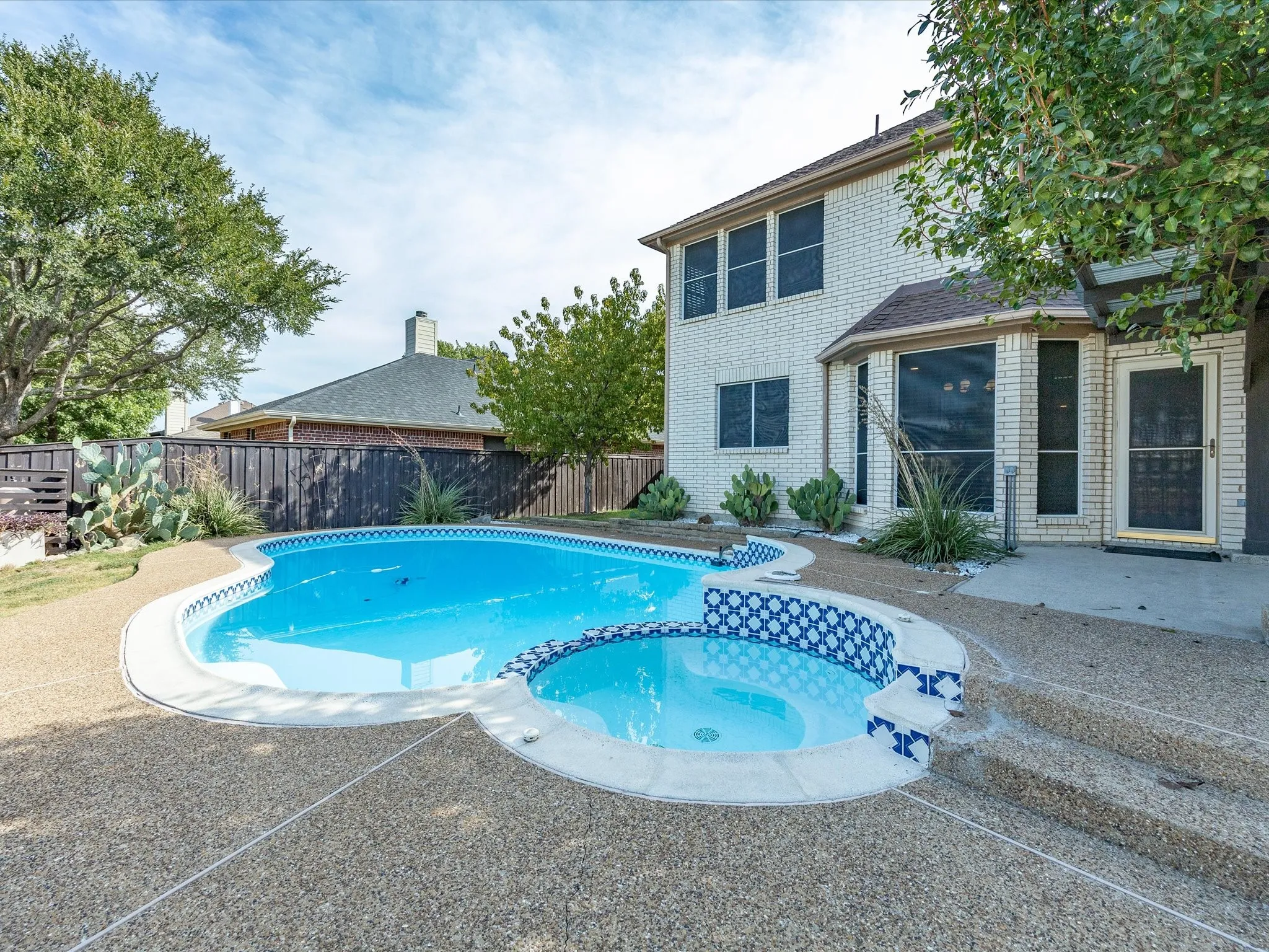 Expansive backyard with a freeform pool and integrated spa featuring decorative blue and white tile