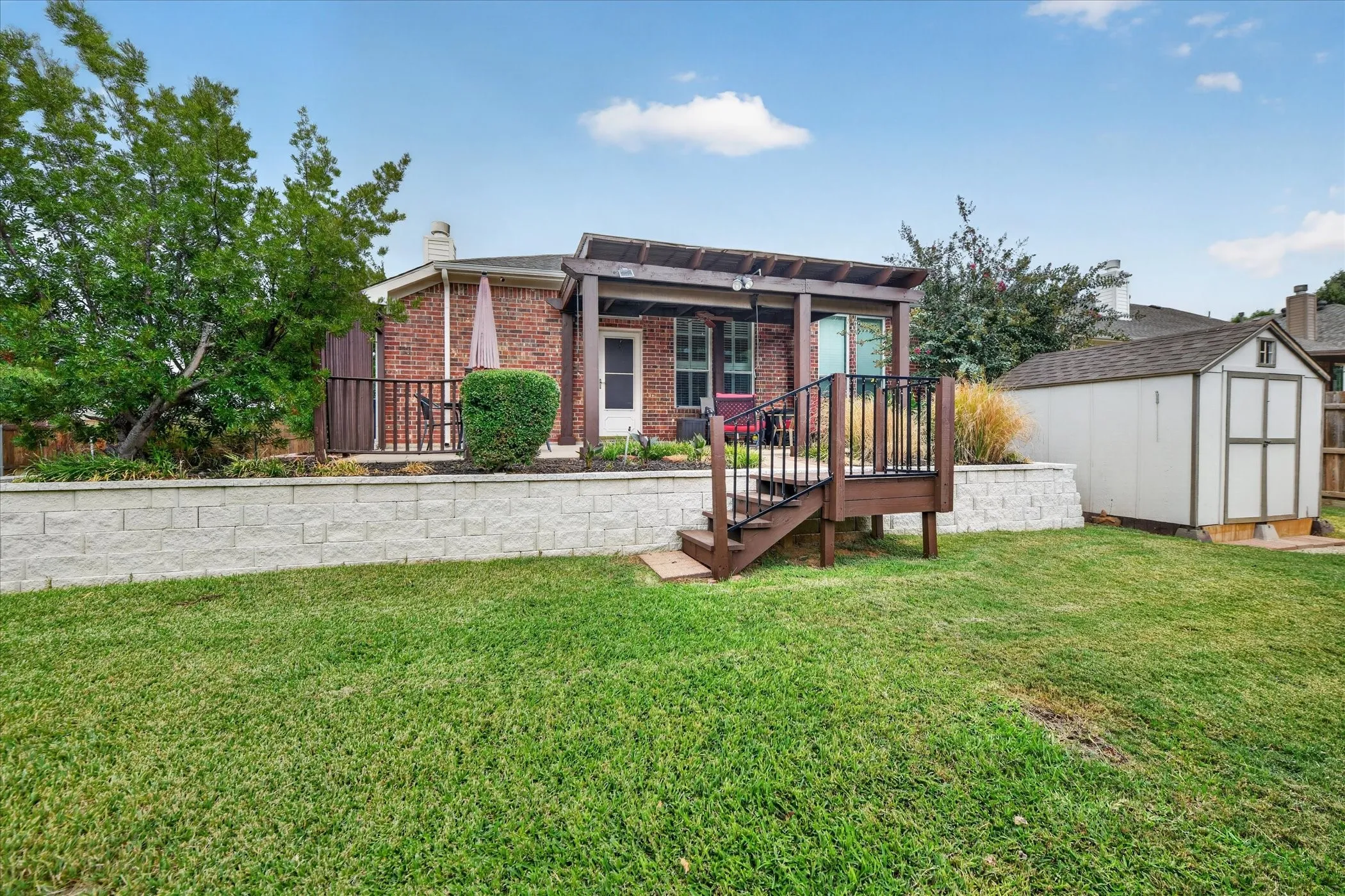 Expansive backyard with a brick-clad exterior, a pergola-covered patio, and a dedicated storage shed