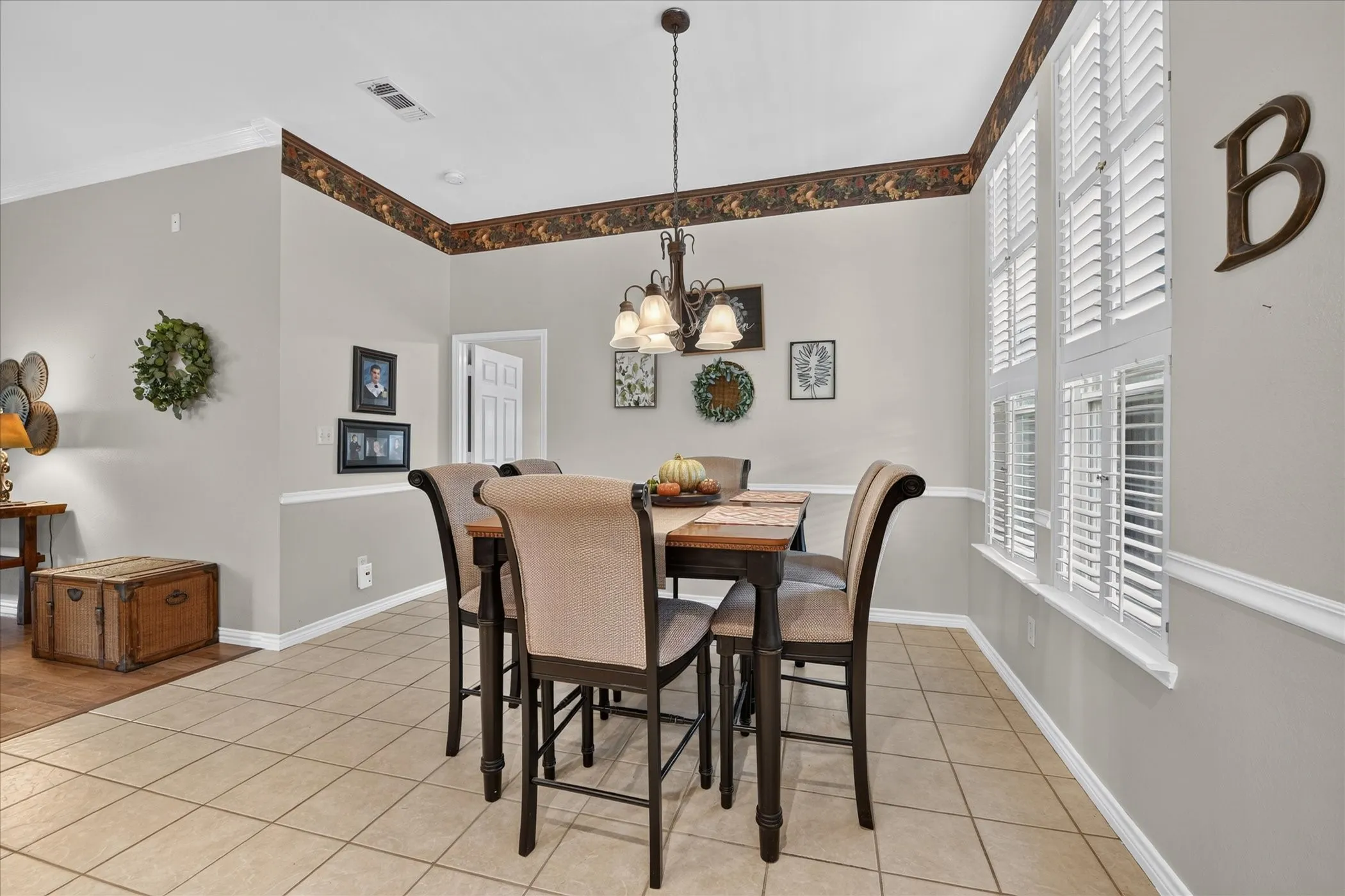 Ceramic tile flooring, crown molding, chair rail molding, decorative lighting fixture, and white plantation shutters