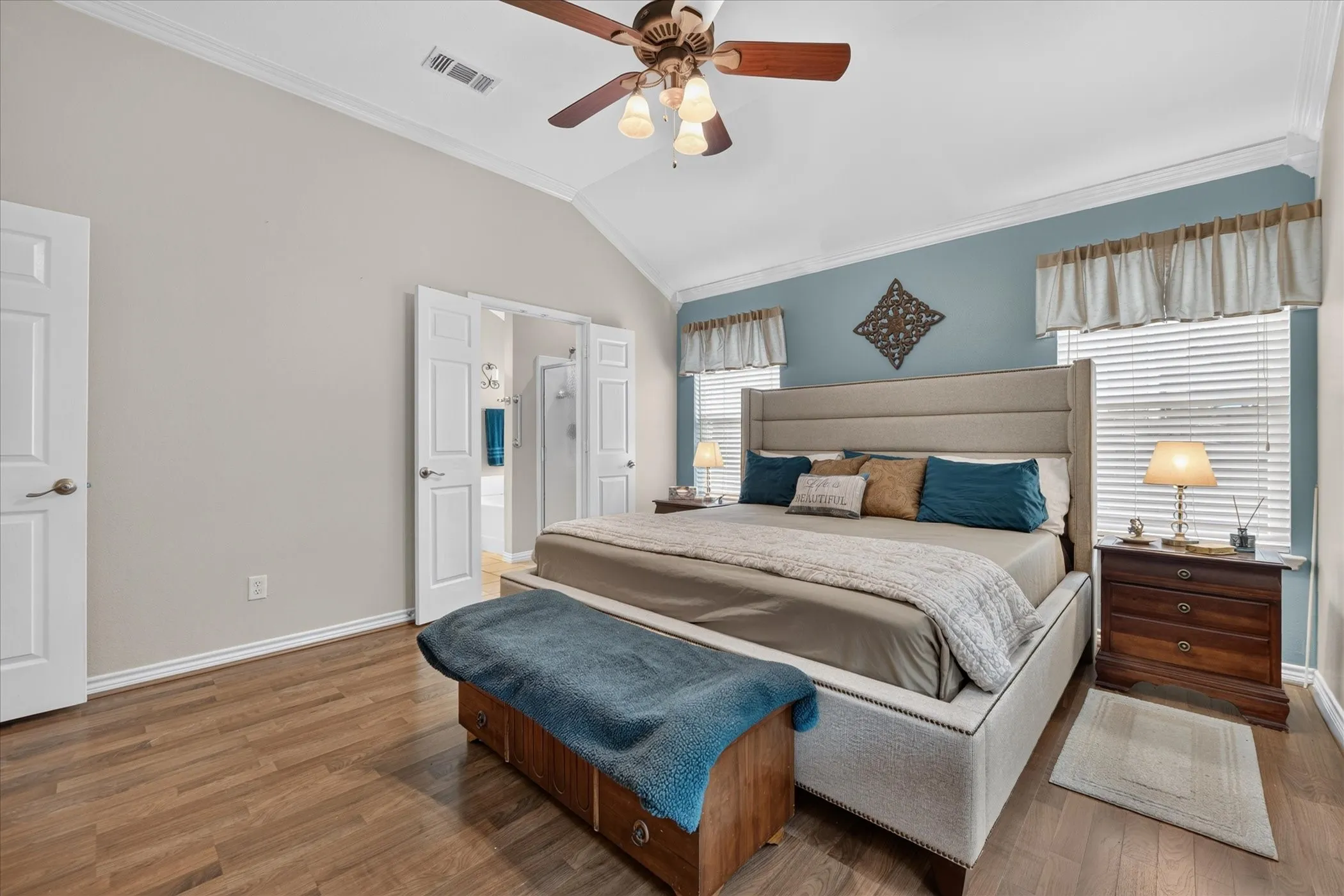 Primary Bedroom Suite featuring vaulted ceilings, wood-finish flooring throughout, and a blue accent wall with coordinating bedding