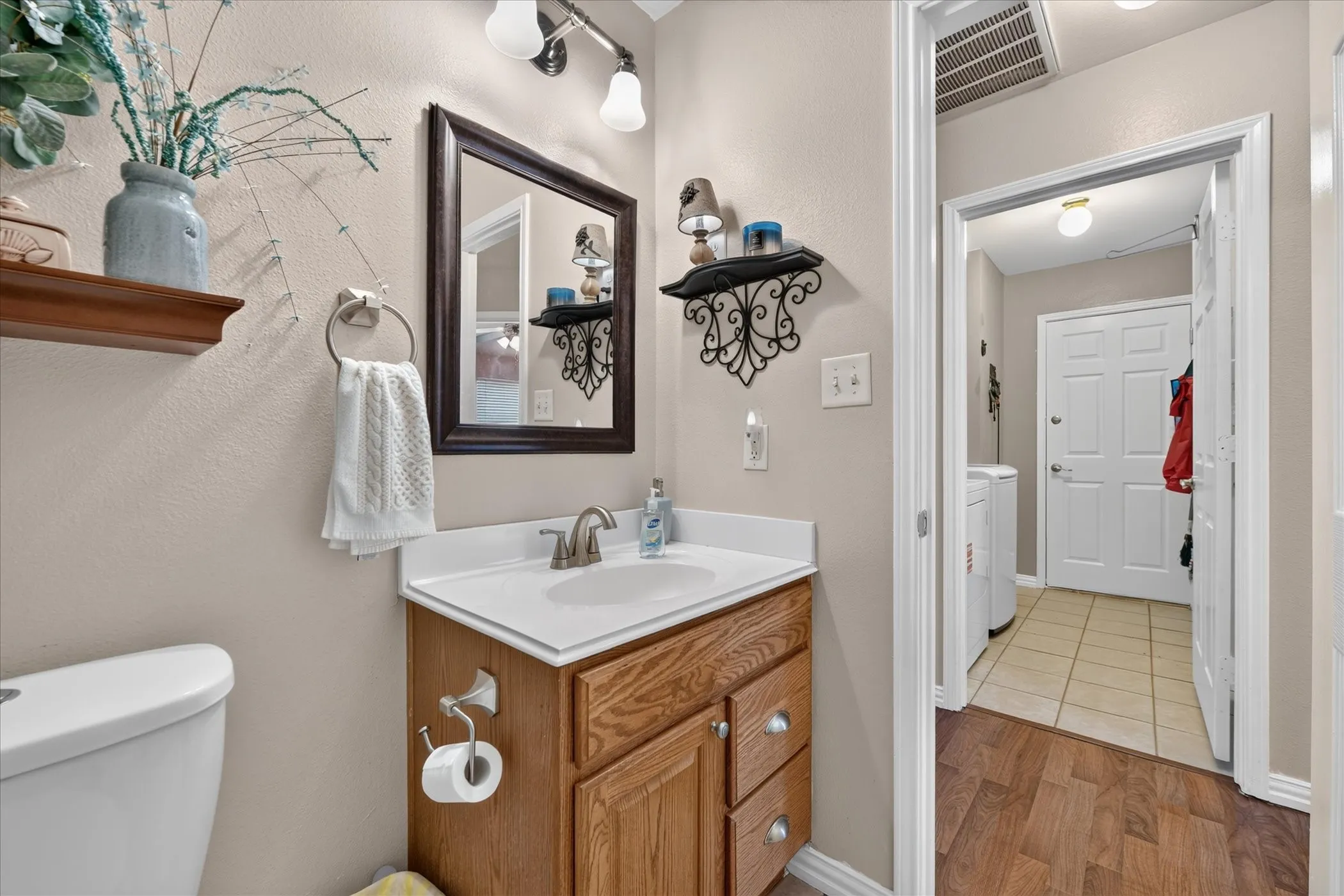 Powder room featuring a single vanity with wood-finish cabinetry, a framed mirror, and a wall-mounted light fixture