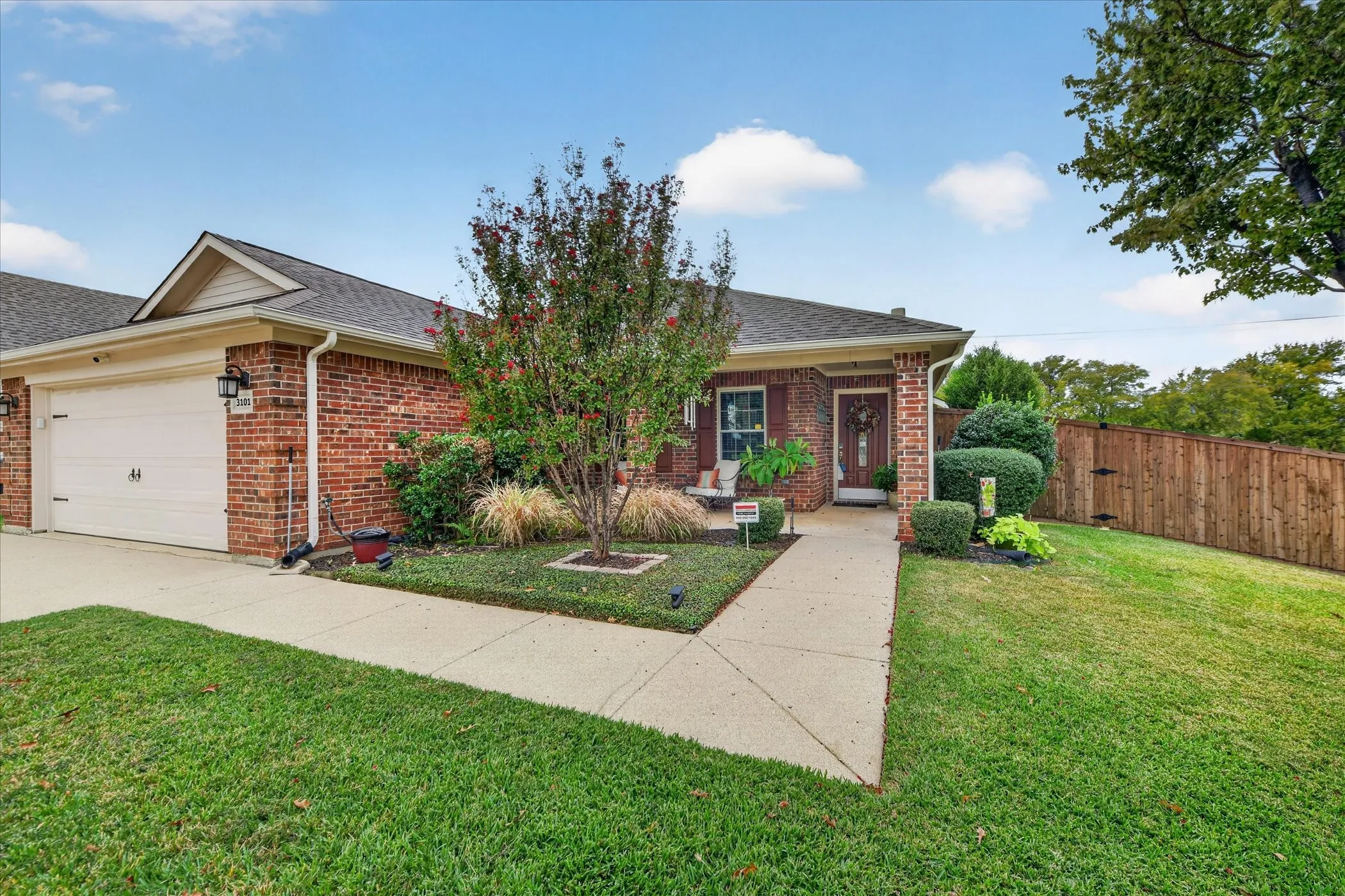 Brick exterior with an attached garage, covered entryway, and a wood privacy fence