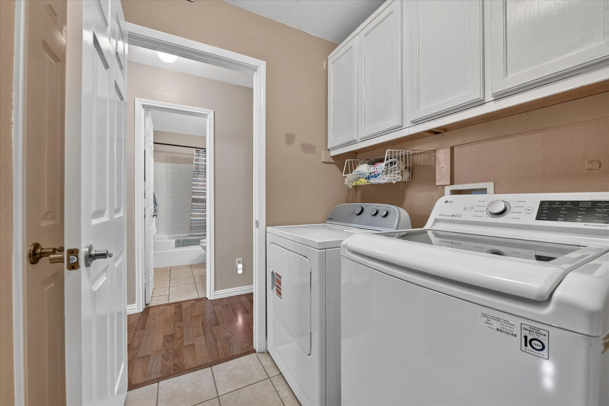 Laundry area featuring overhead cabinetry, wood-finish flooring, and light-toned wall paint