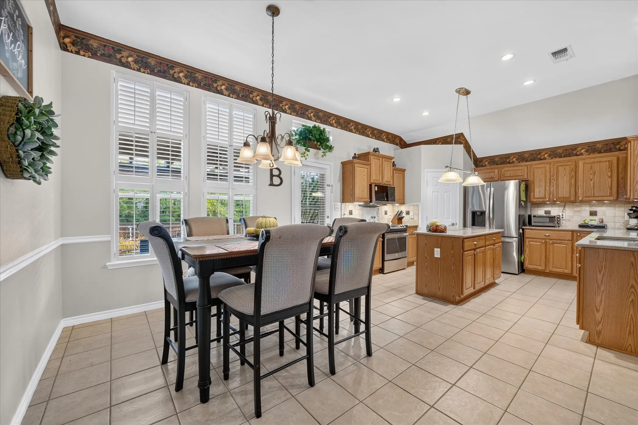 Kitchen with vaulted ceiling, wood-finish cabinetry, stainless steel appliances, and a central island