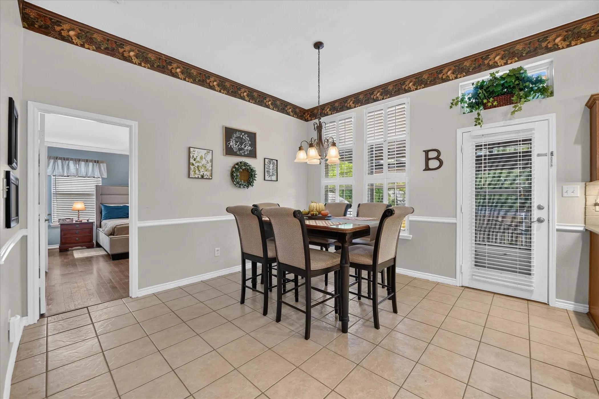 Tile flooring, crown molding, chair rail molding, pendant lighting, and a glass-paneled door