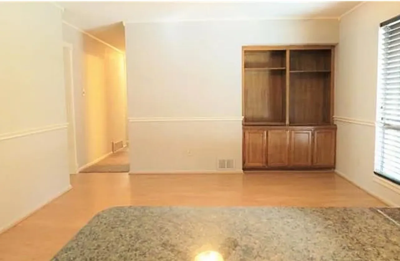 Wood-finish flooring, built-in shelving, window with blinds, and decorative wall molding