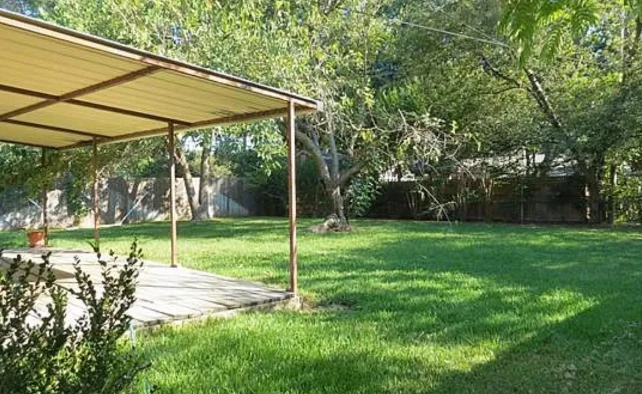 Expansive backyard featuring a covered patio, a substantial lawn, and a perimeter fence