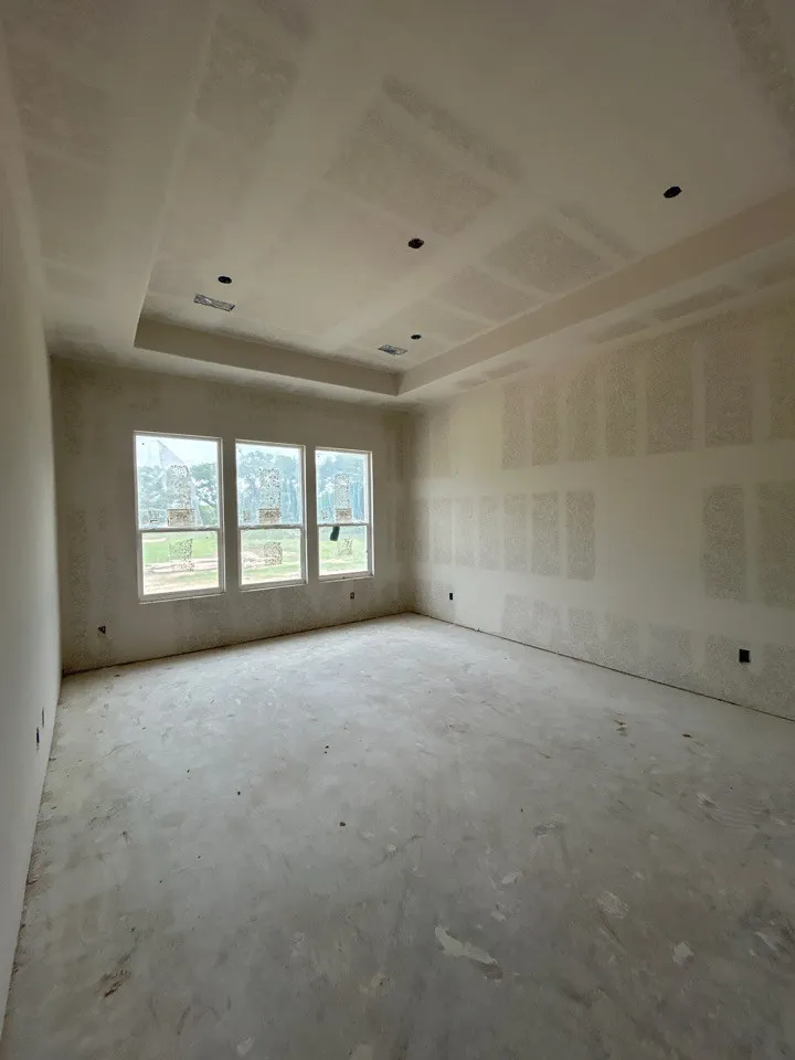 Tray ceiling with recessed lighting, triple window installation, smooth wall surfaces, and concrete subfloor