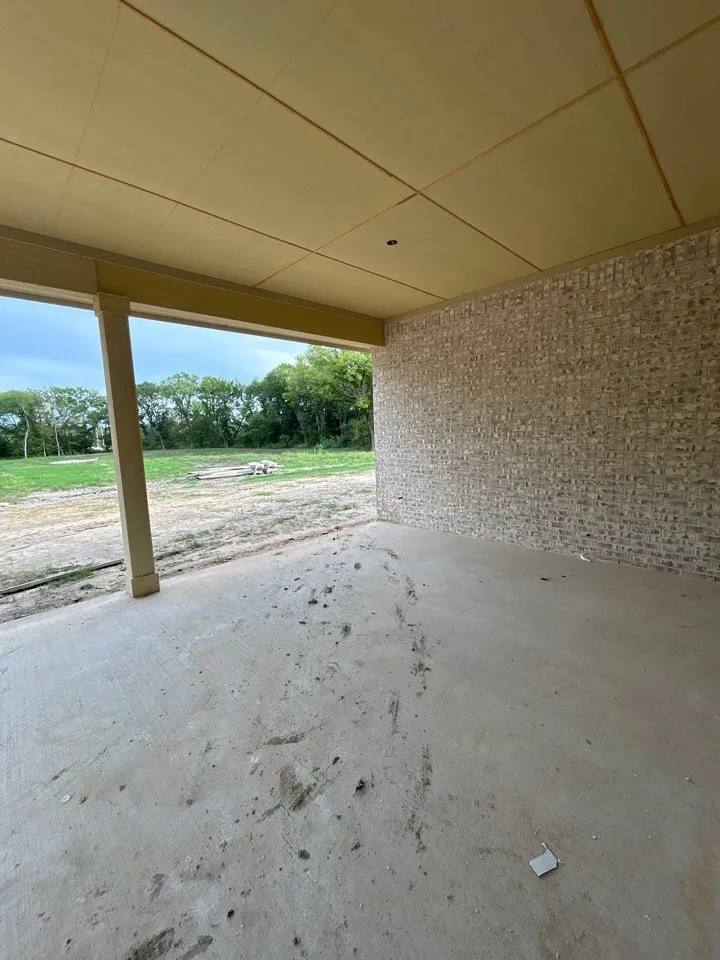 Covered outdoor patio with a concrete floor, brick wall, and exposed wood ceiling