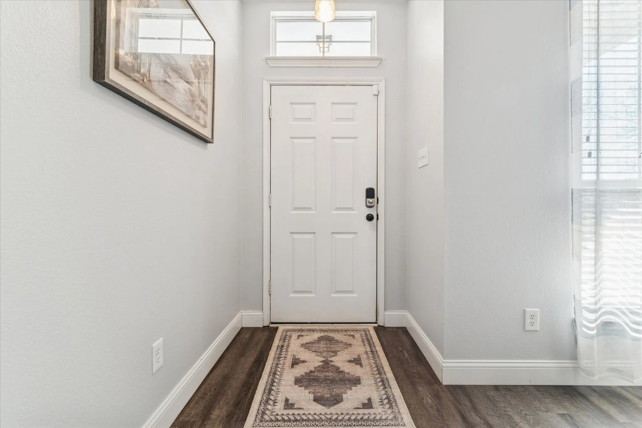 Entryway with wood-finish flooring, a white paneled door, and an overhead transom window