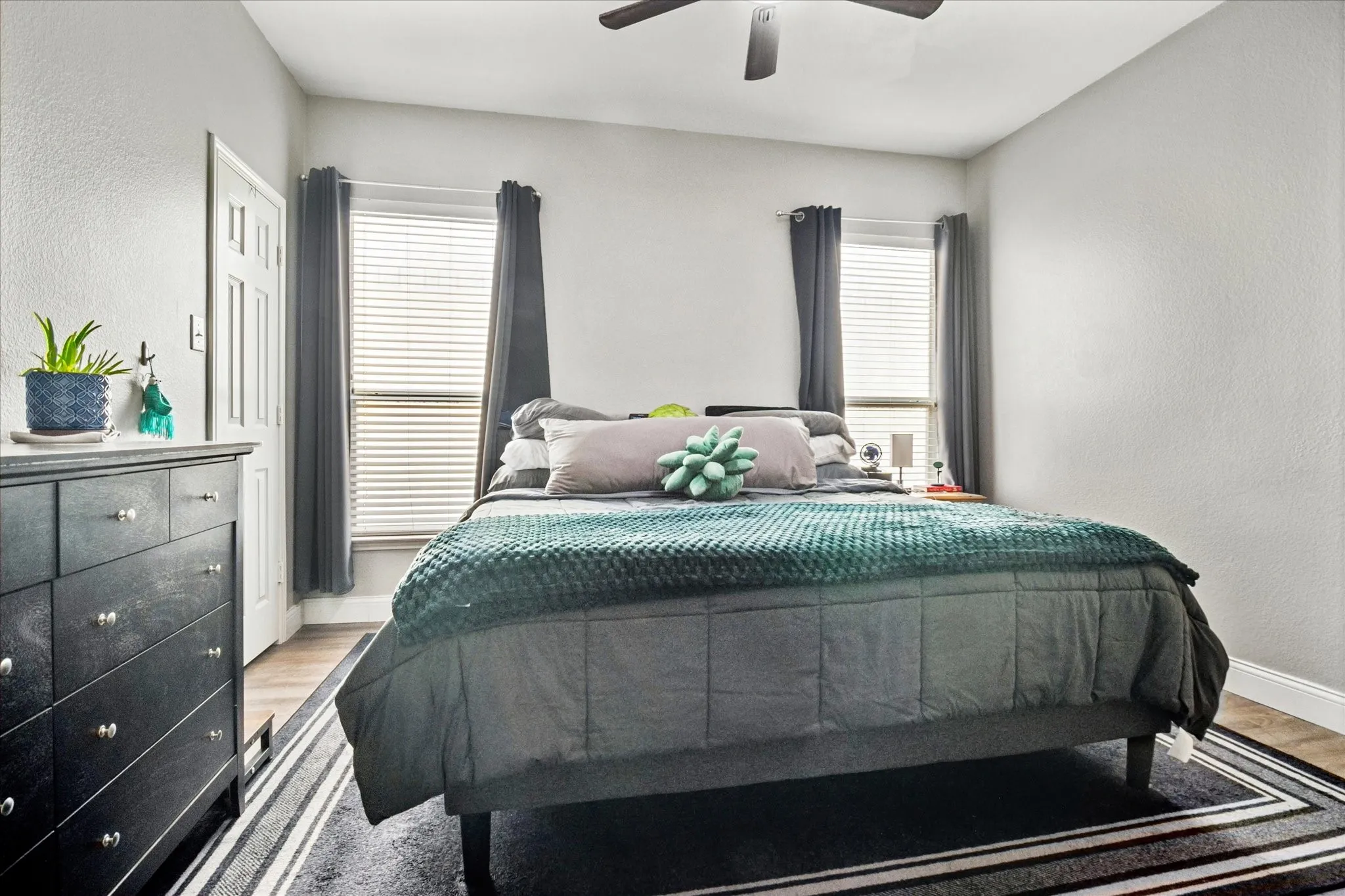 Wood-finish flooring, white walls, and a ceiling fan with integrated lighting