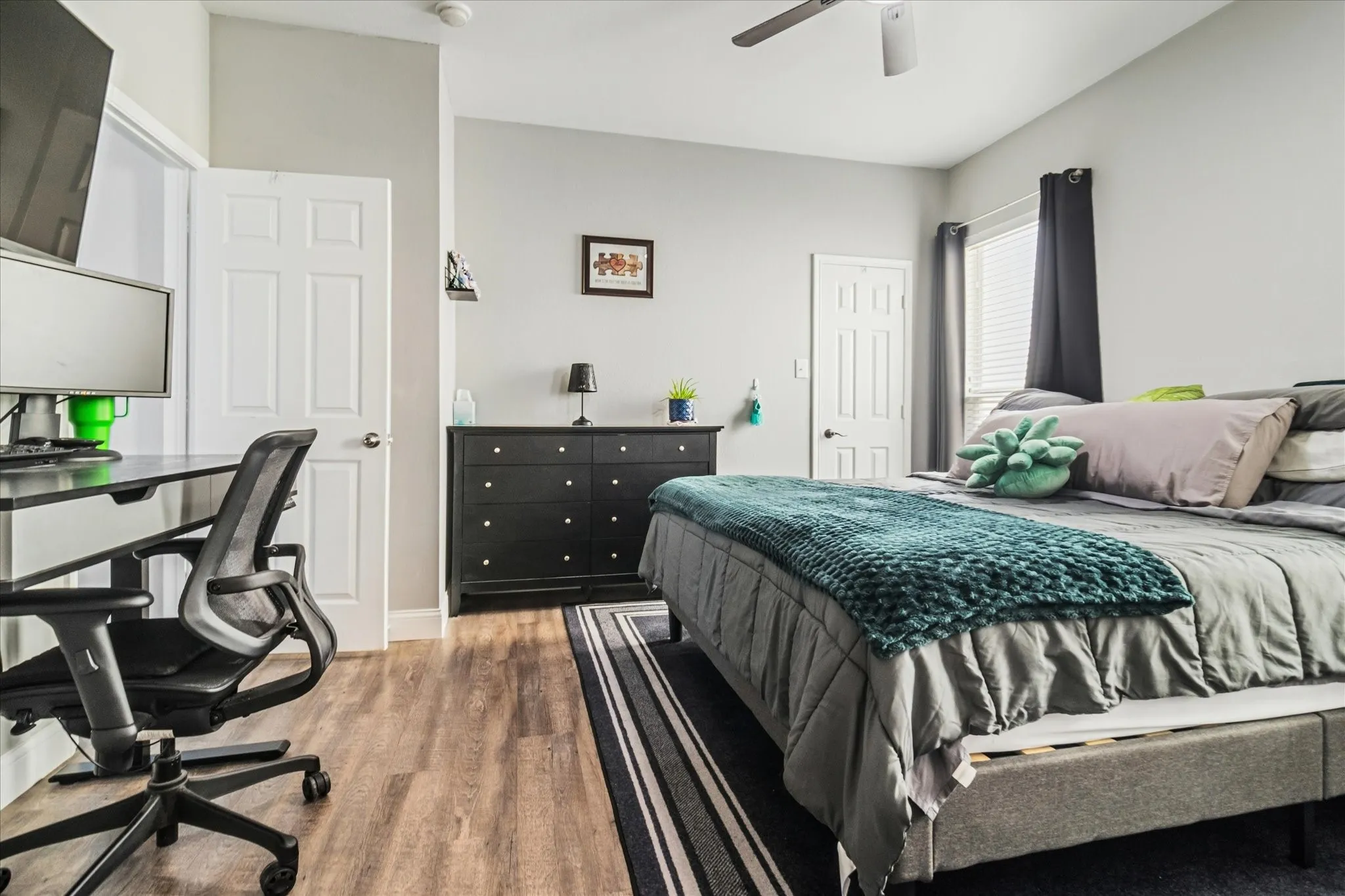 Wood-finish flooring, ceiling fan, white paneled doors, and window with blinds
